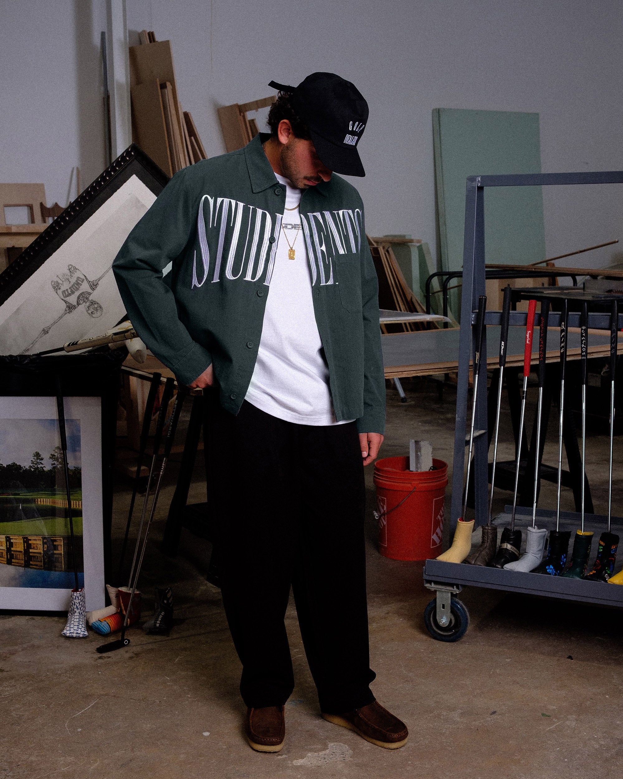 Person wearing a green jacket with 'STUDENTS' text in a workshop setting
