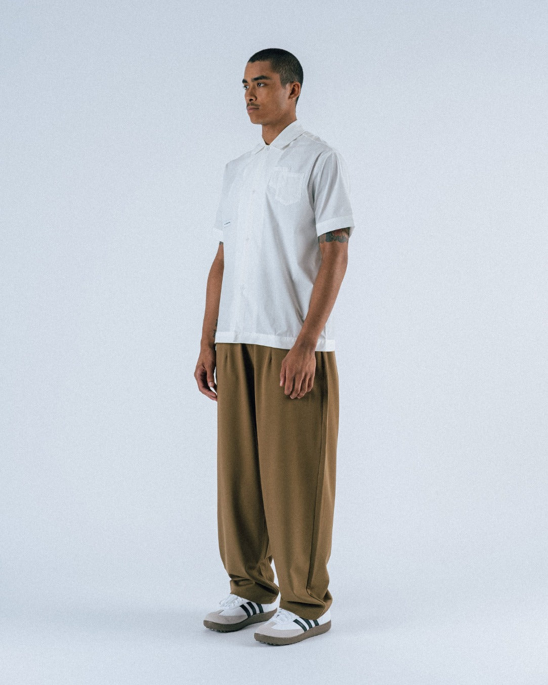 Person wearing a white t-shirt and brown pants on a white background