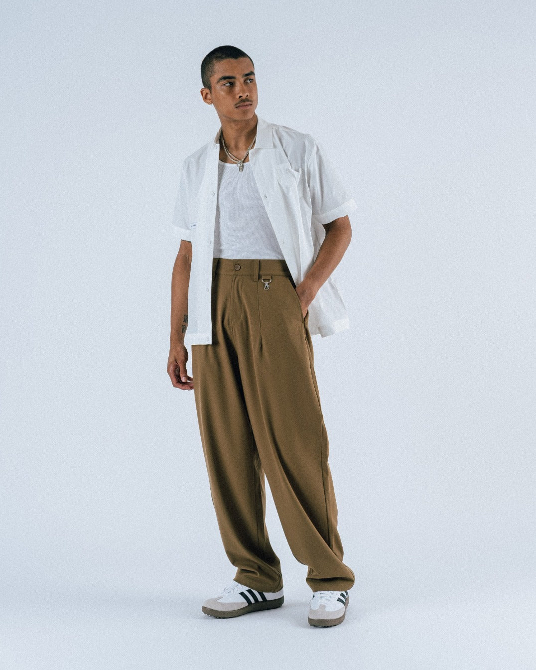 Person wearing a white shirt, beige pants, and black and white sneakers on a light gray background