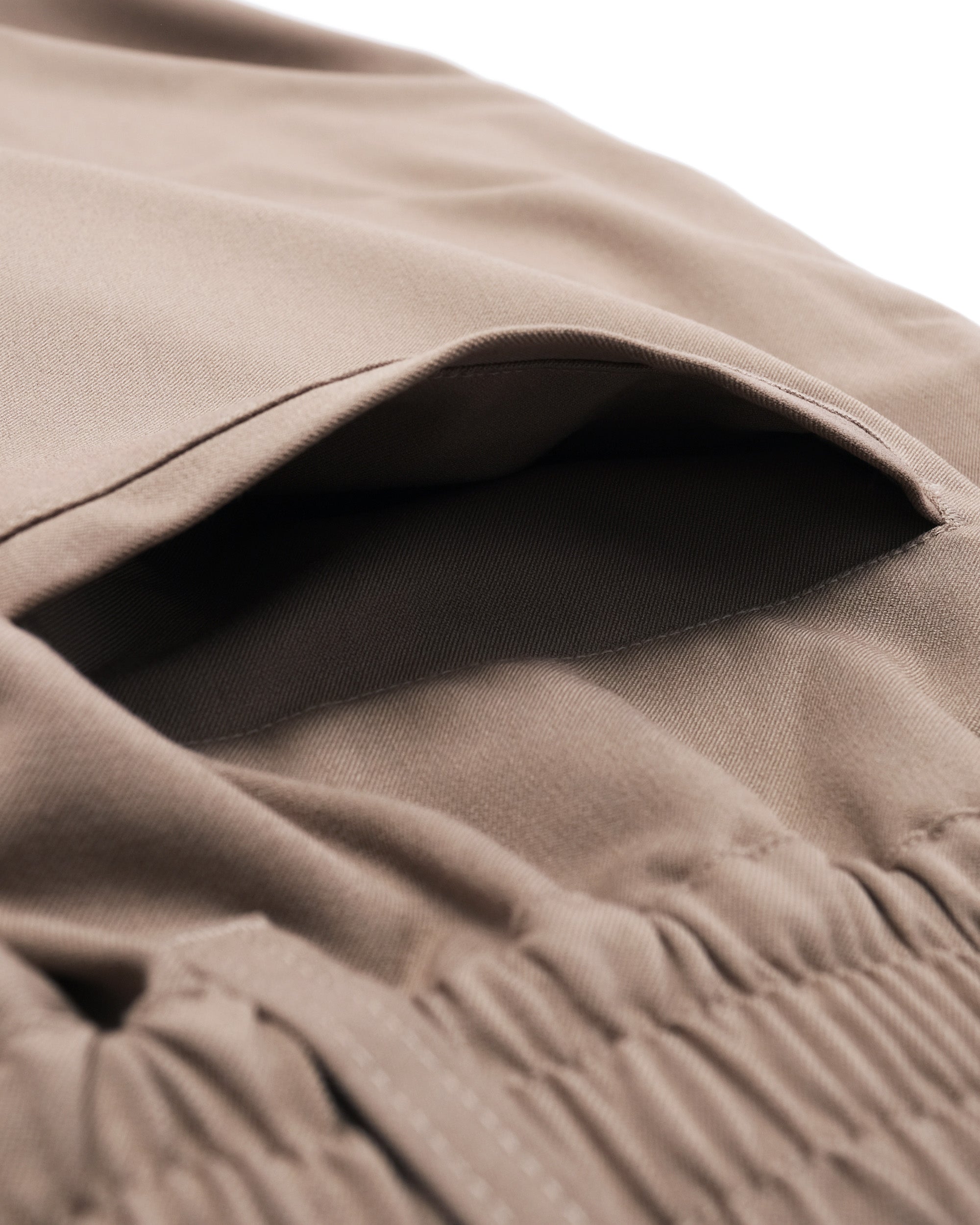 Close-up of a brown fabric with a pocket detail on a white background
