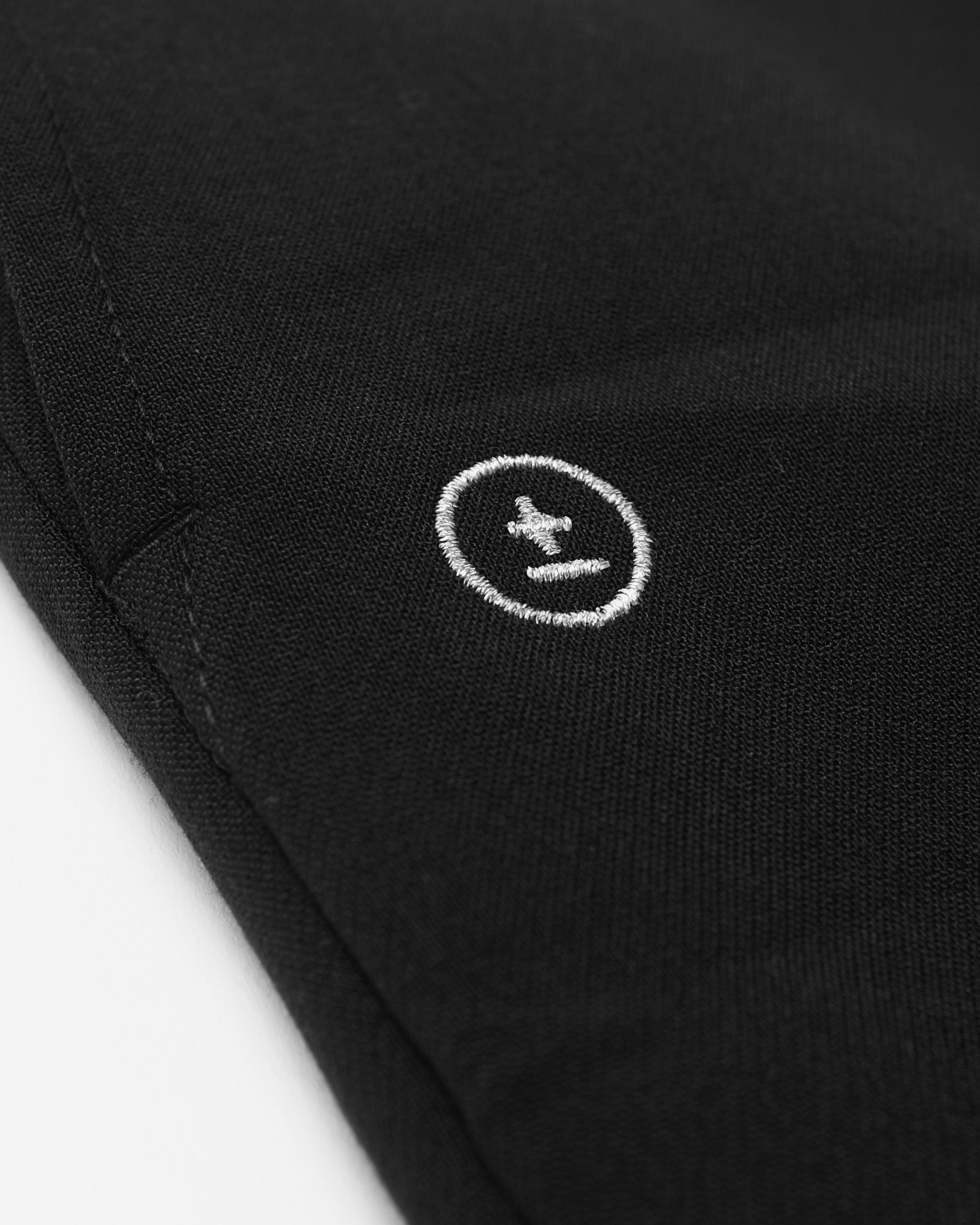Close-up of a black garment with a white logo on a light gray background