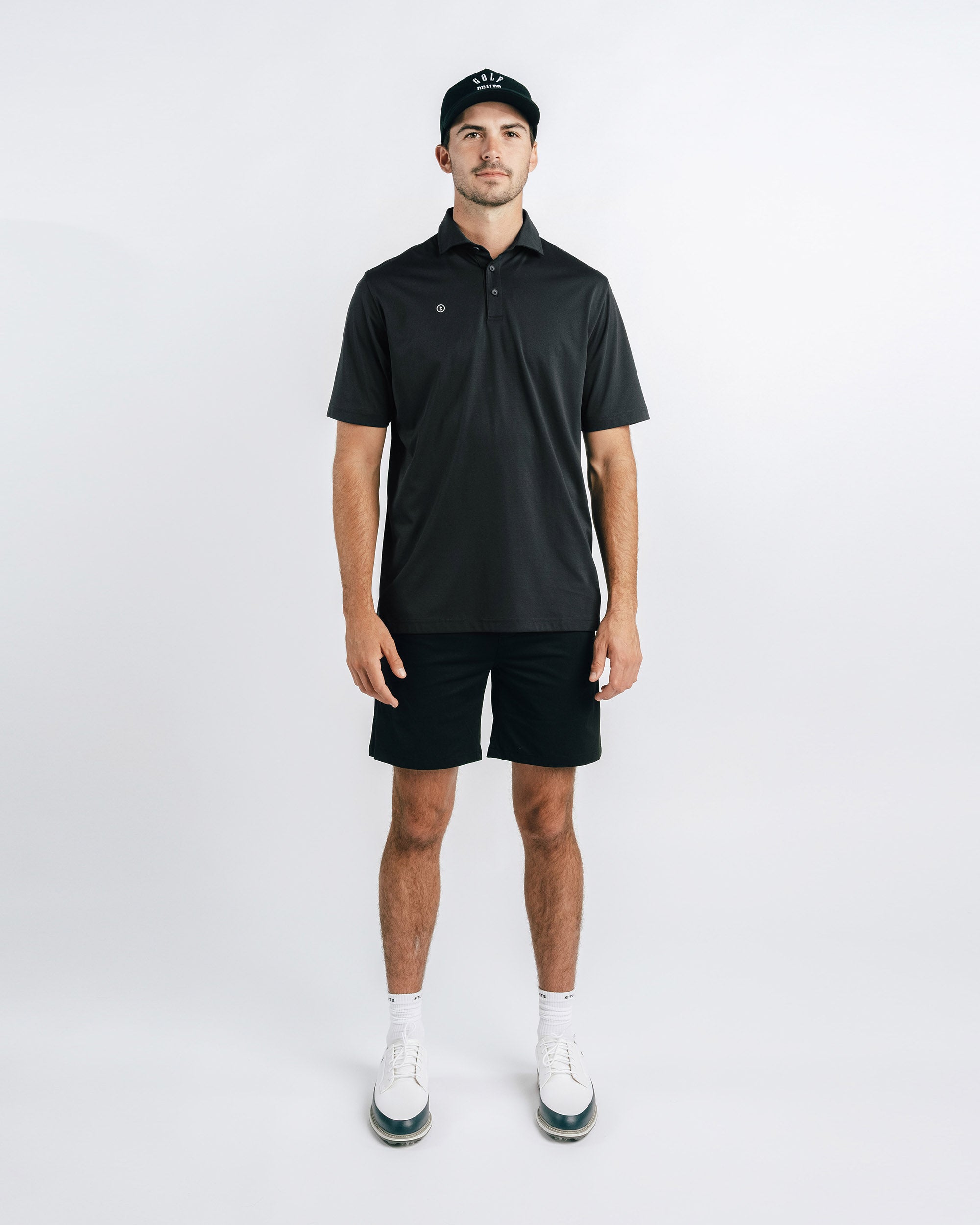 Man wearing a black polo shirt and shorts with a white background