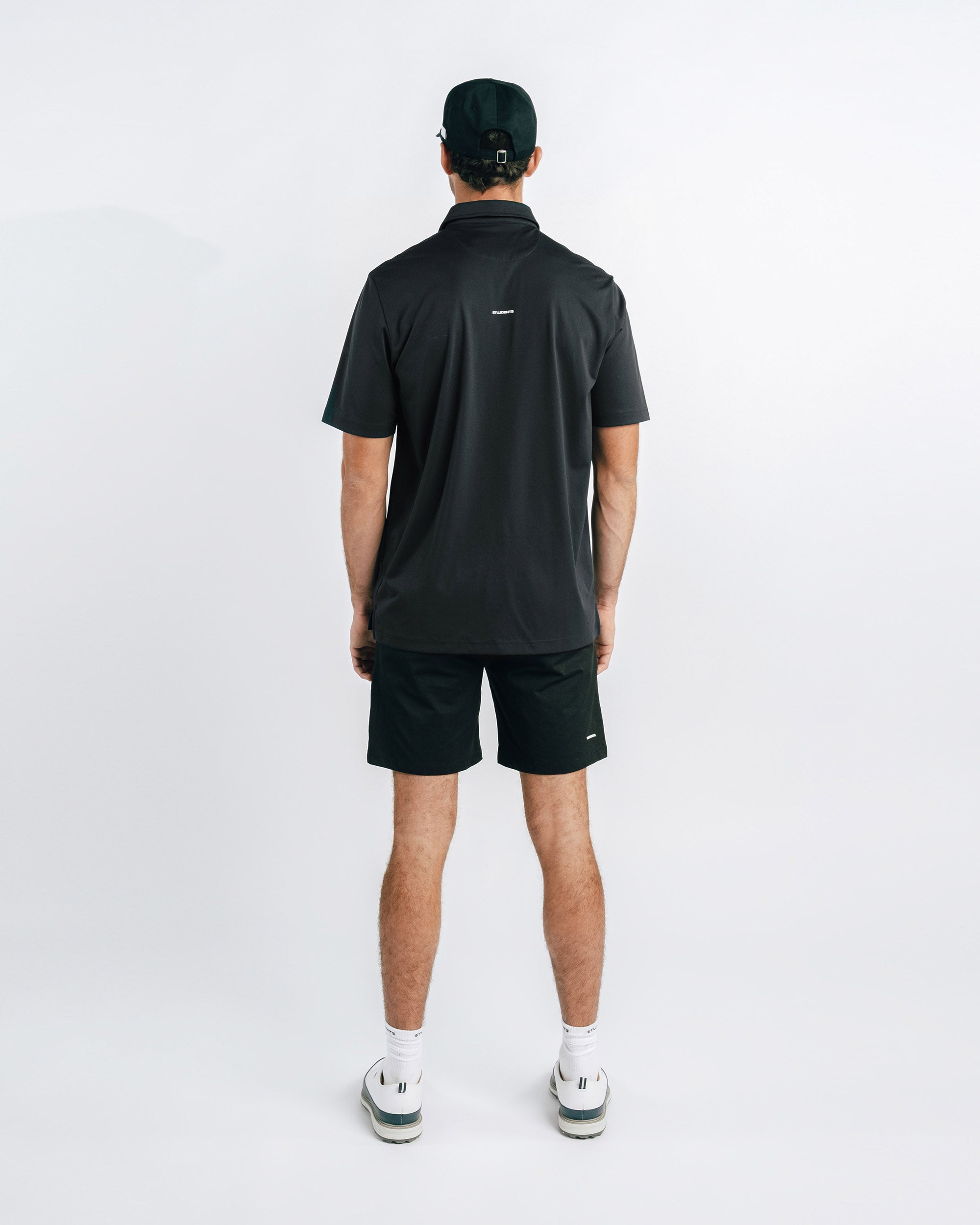 Person wearing a black polo shirt and shorts on a white background