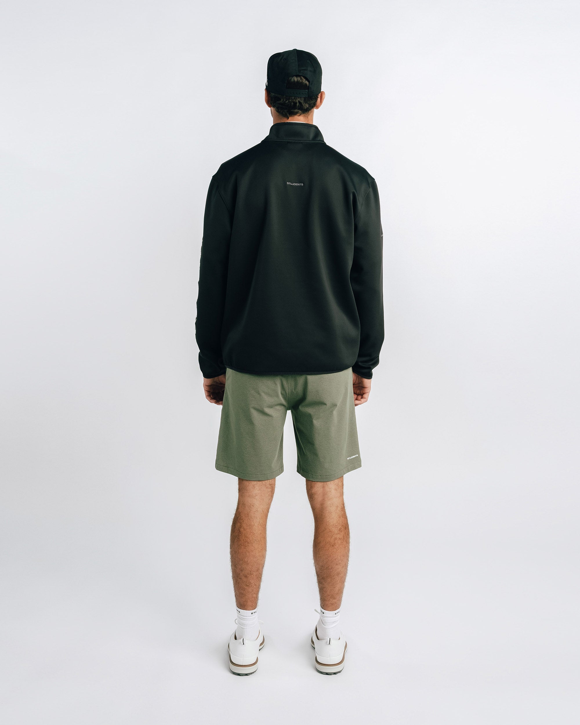 Person wearing a black jacket and green shorts on a white background