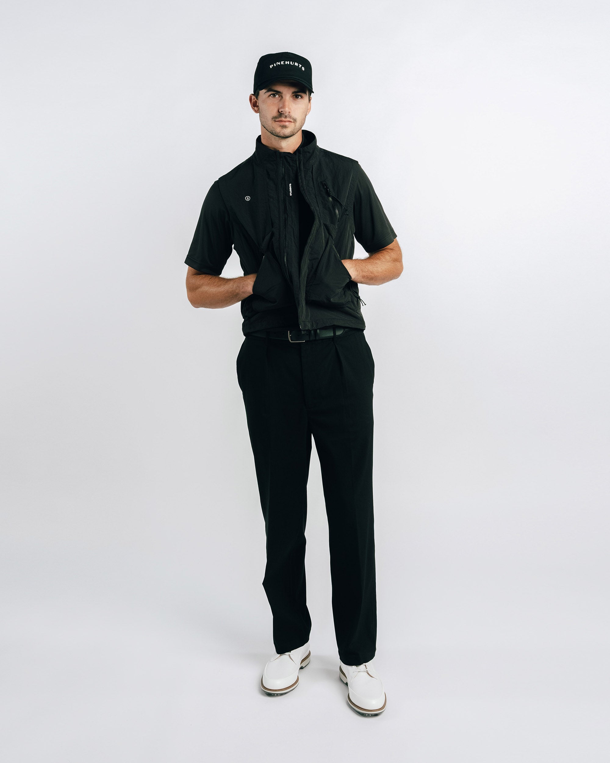 Man wearing a black outfit with a cap on a white background