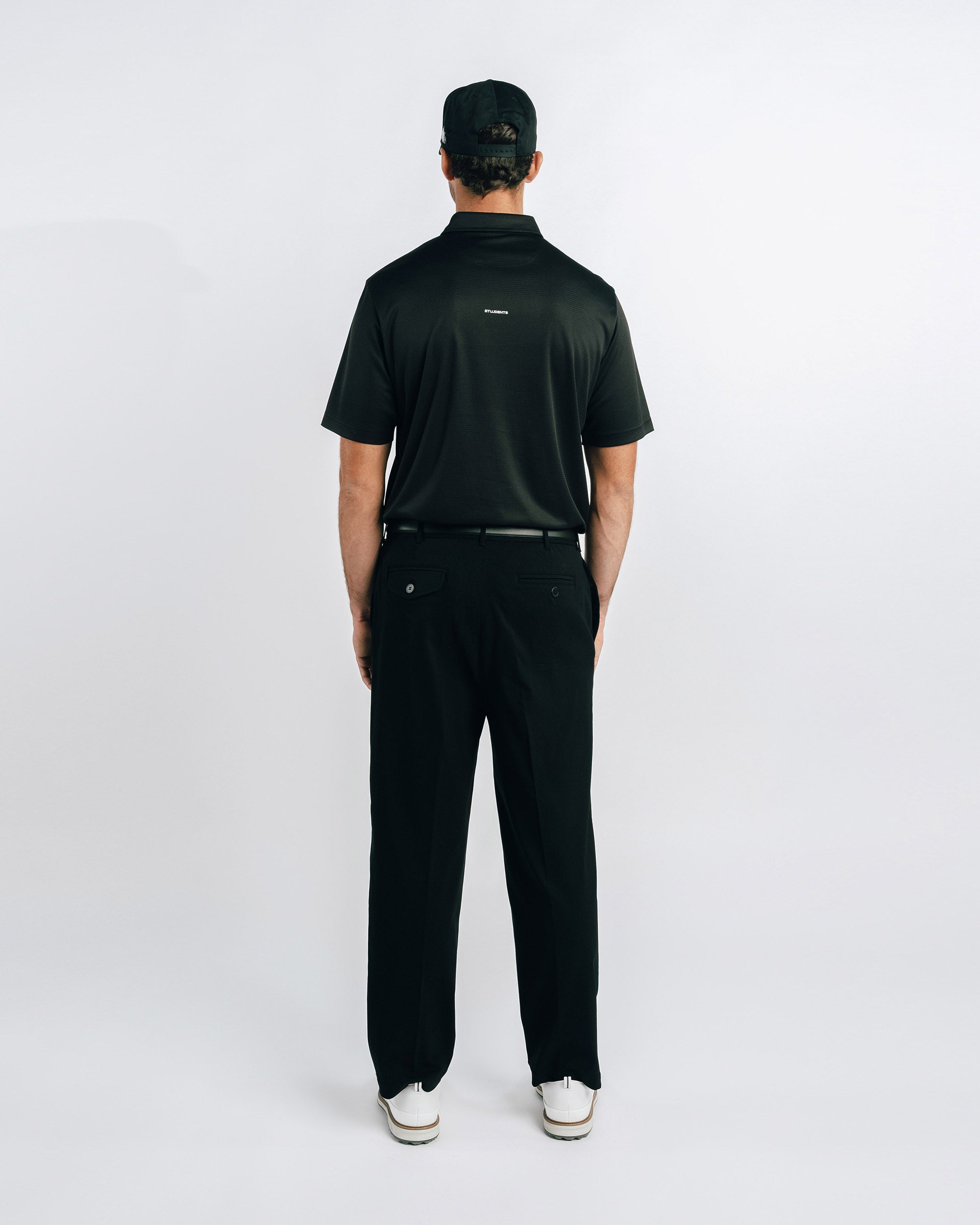 Person wearing a black polo shirt and pants on a white background