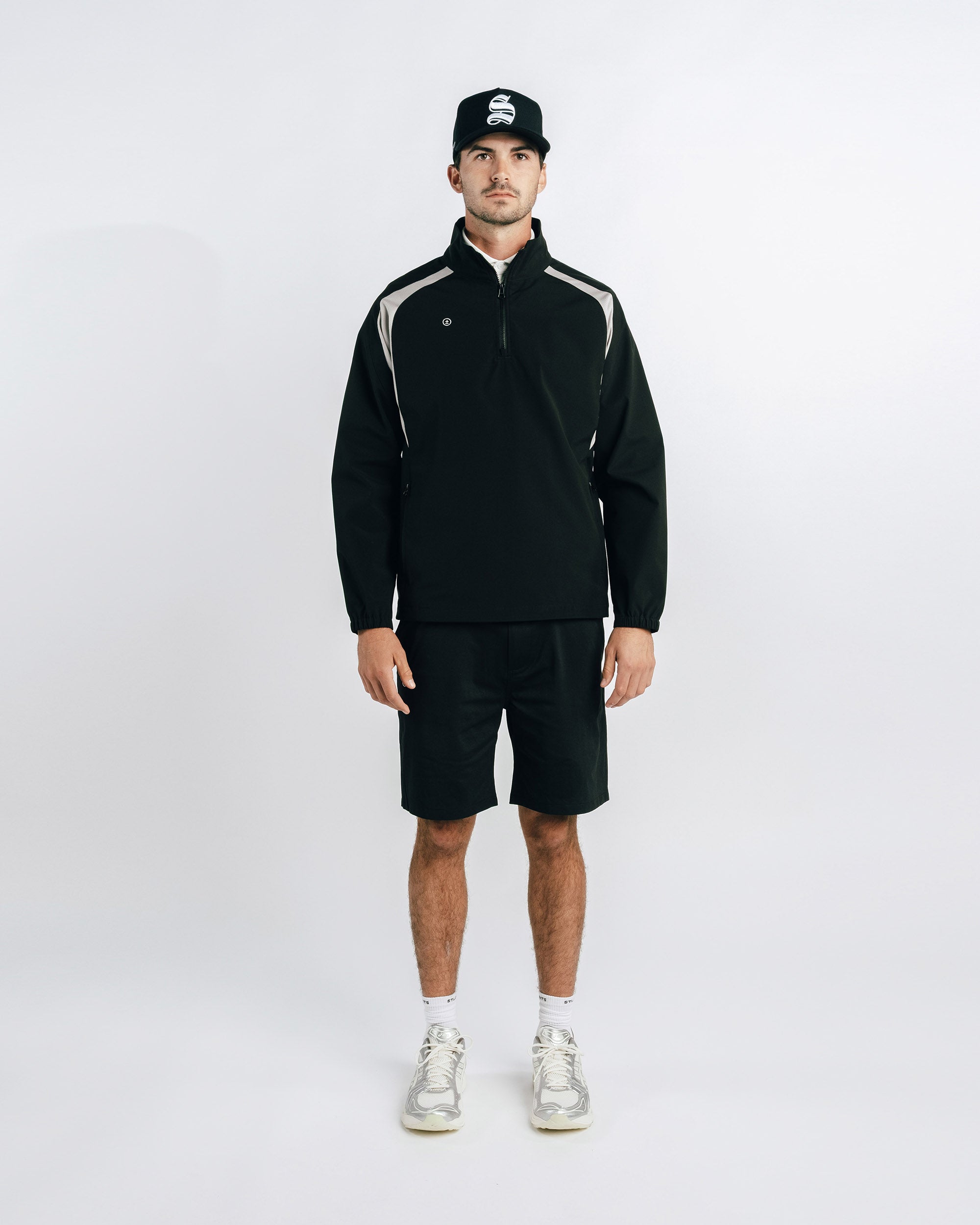 Man wearing a black outfit with white accents on a white background