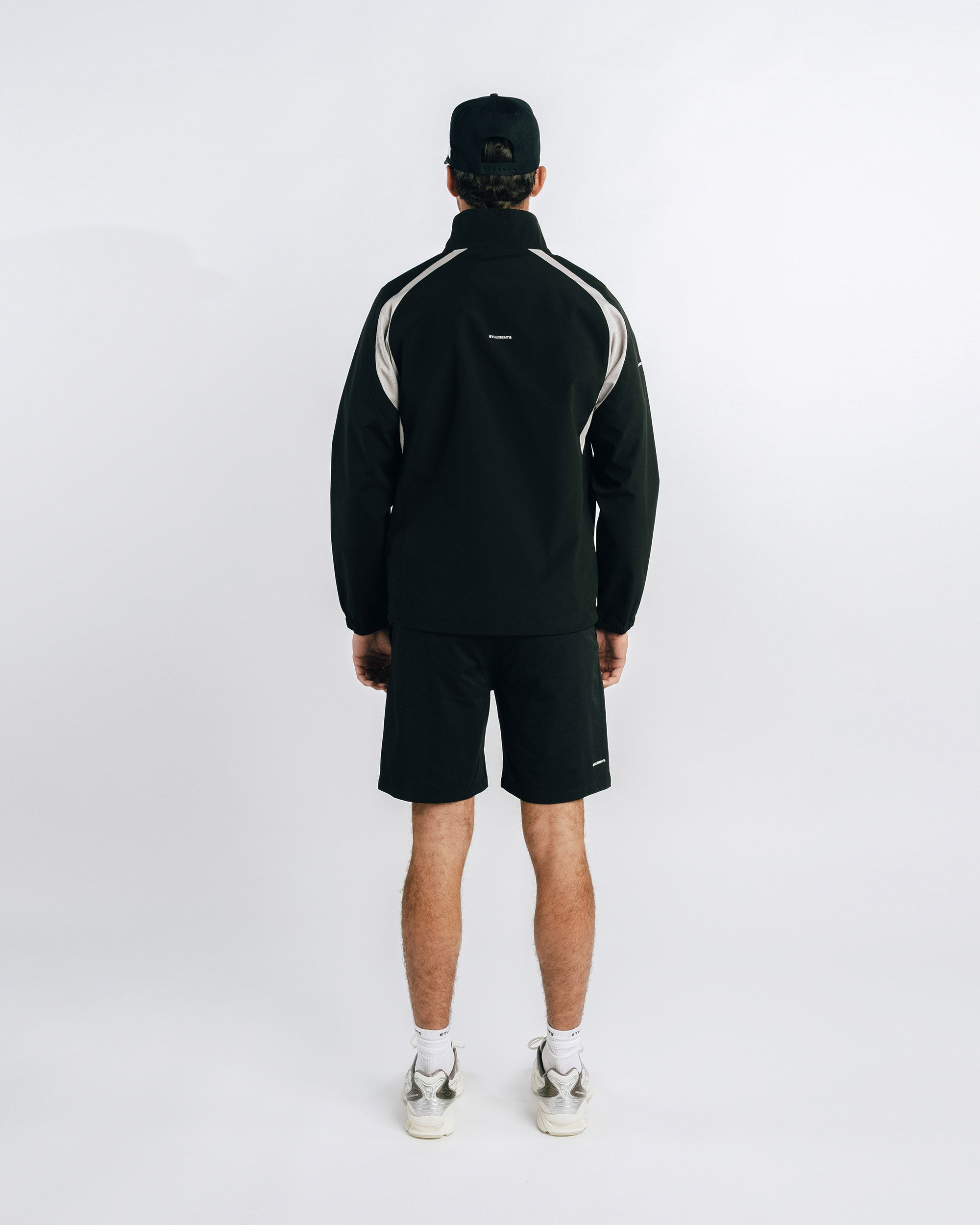 Person wearing a black tracksuit with white accents on a white background