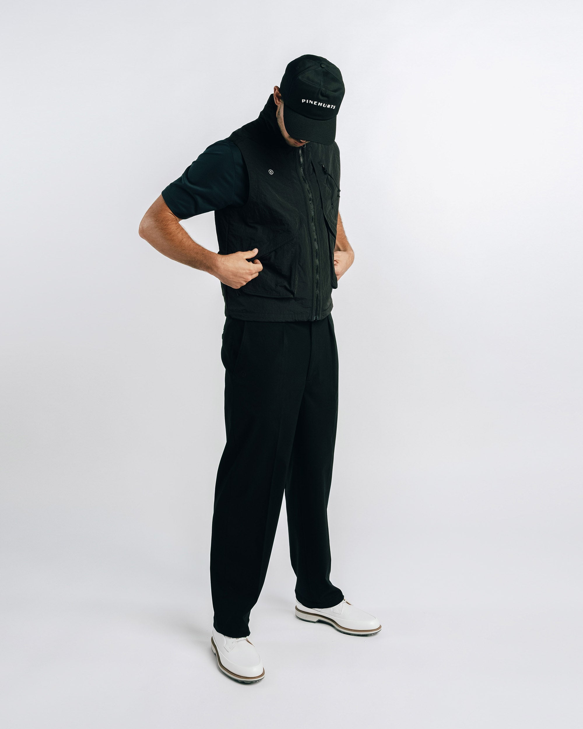 Person wearing a black outfit with a vest and pants on a white background