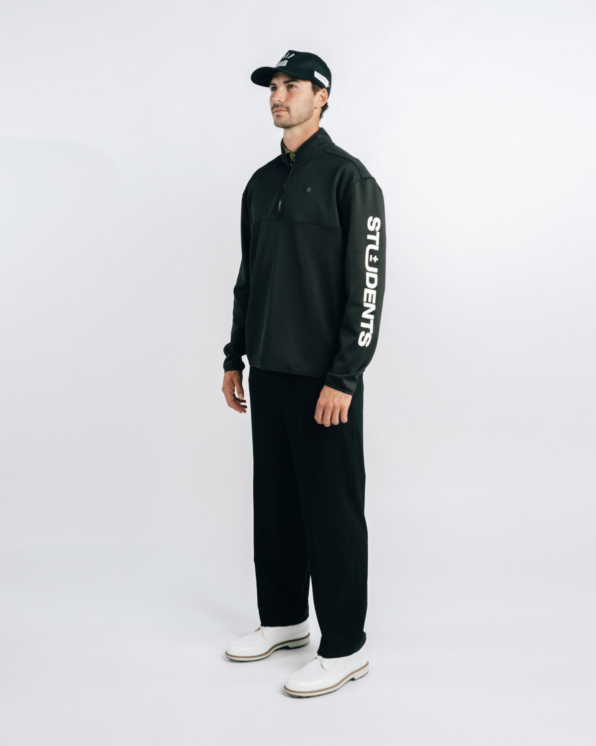 Man wearing a black outfit with branding on a white background