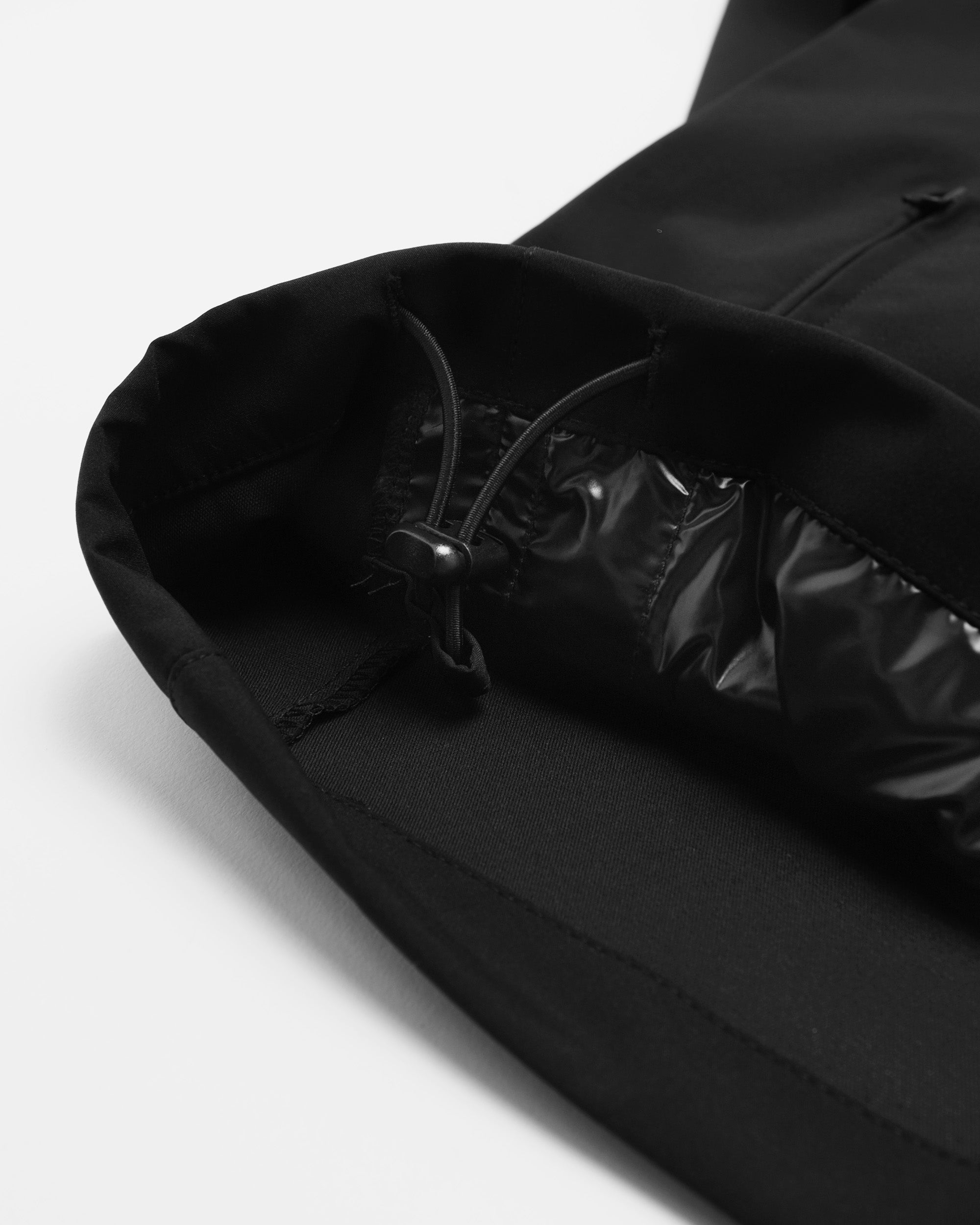 Close-up of a black jacket with a hood on a light gray background