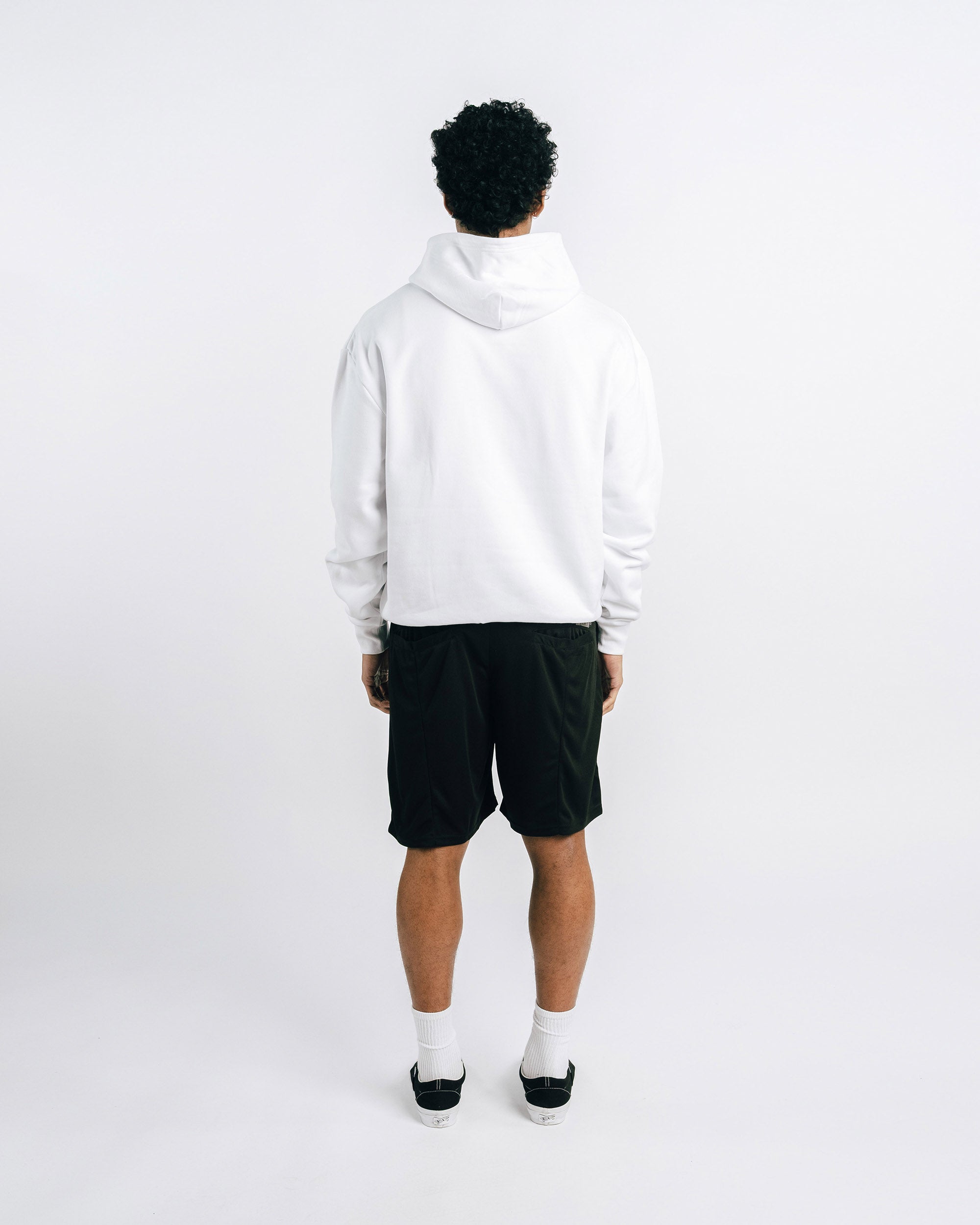 Person wearing a white hoodie and black shorts on a white background