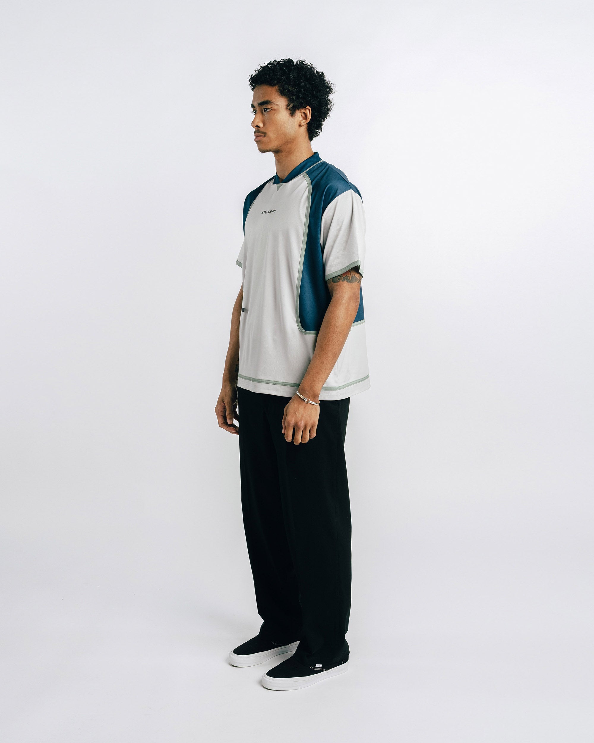 Person wearing a two-tone shirt and black pants on a white background