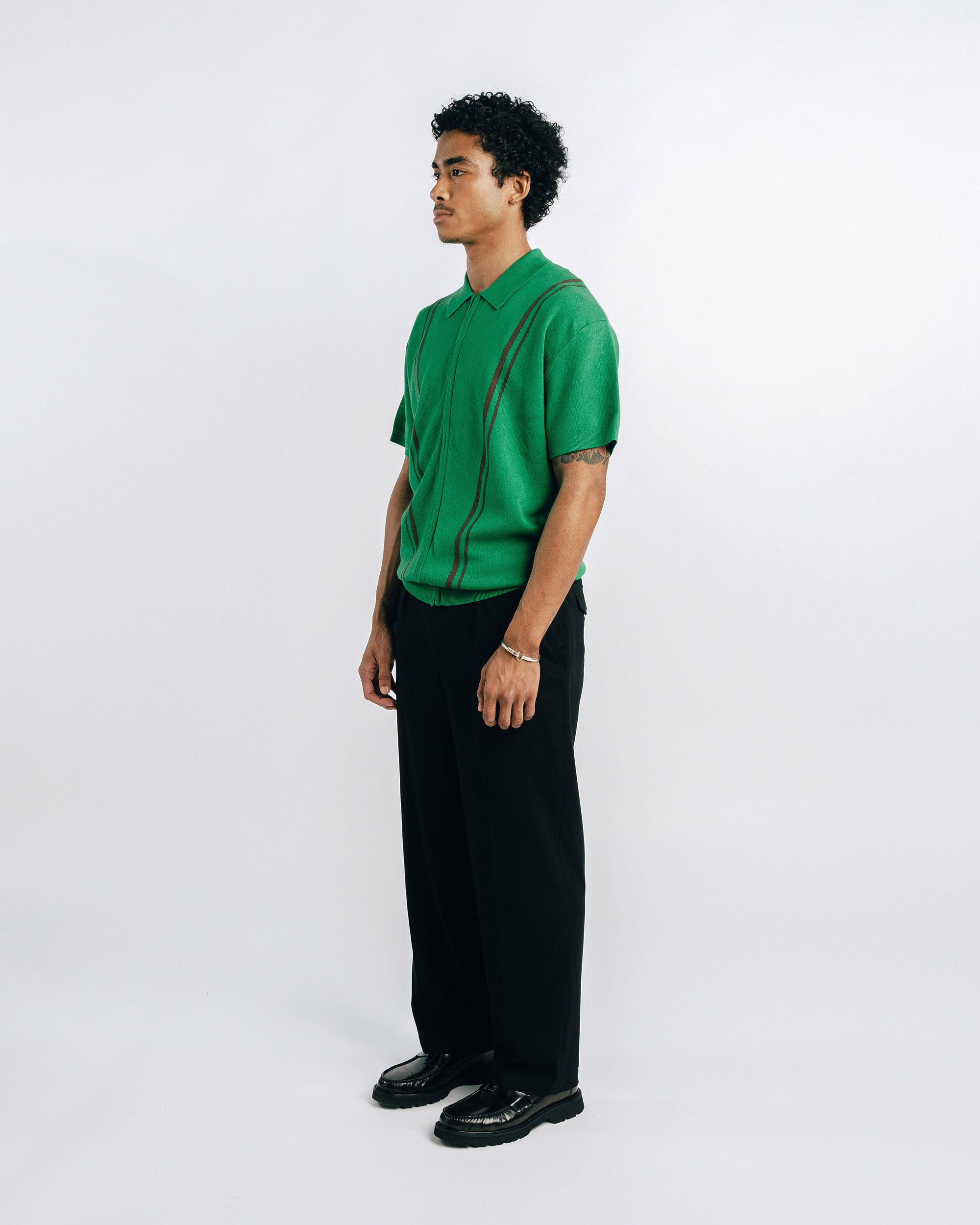 Person wearing a green shirt with suspenders on a white background