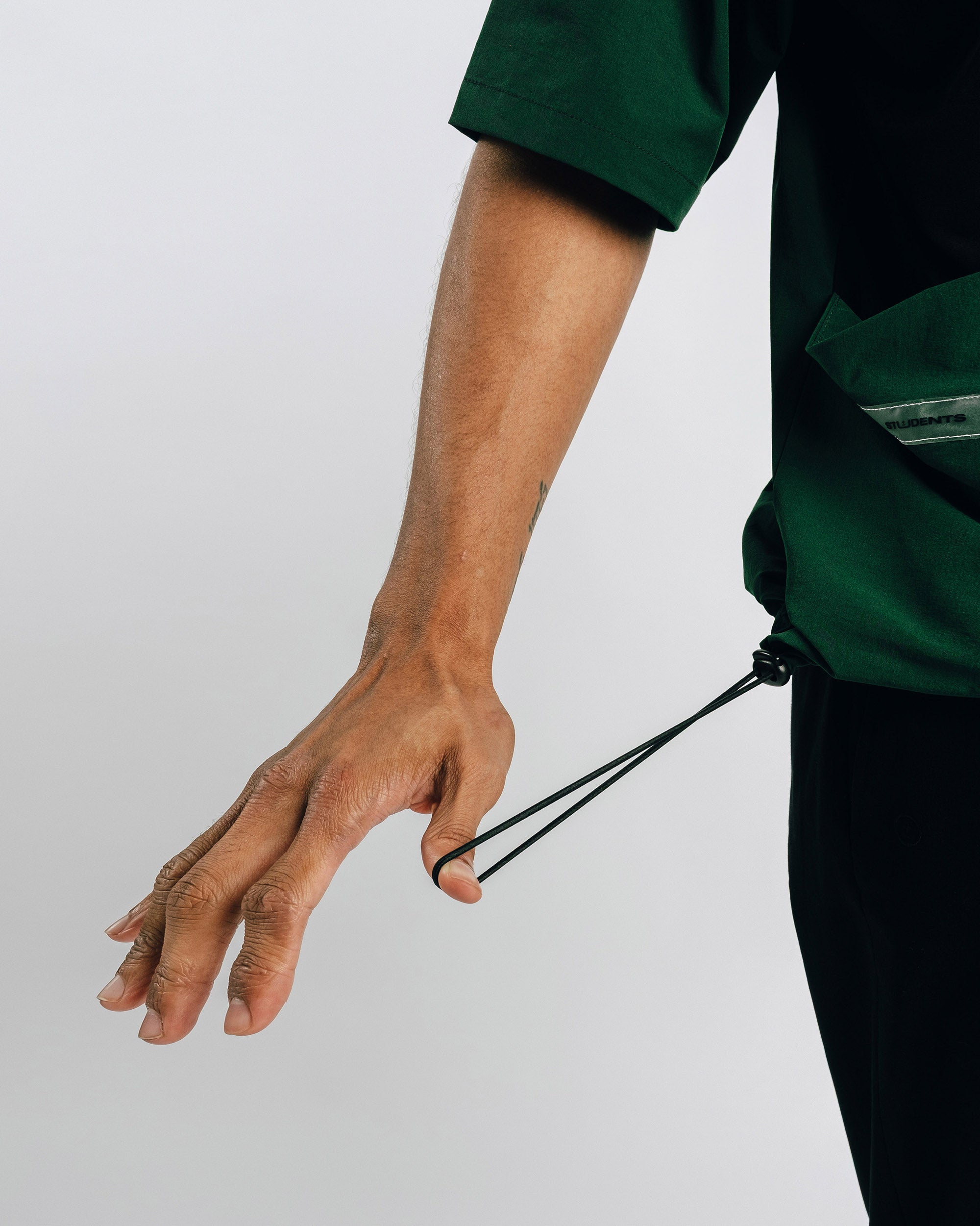 Person wearing green scrubs holding a black lanyard against a light gray background