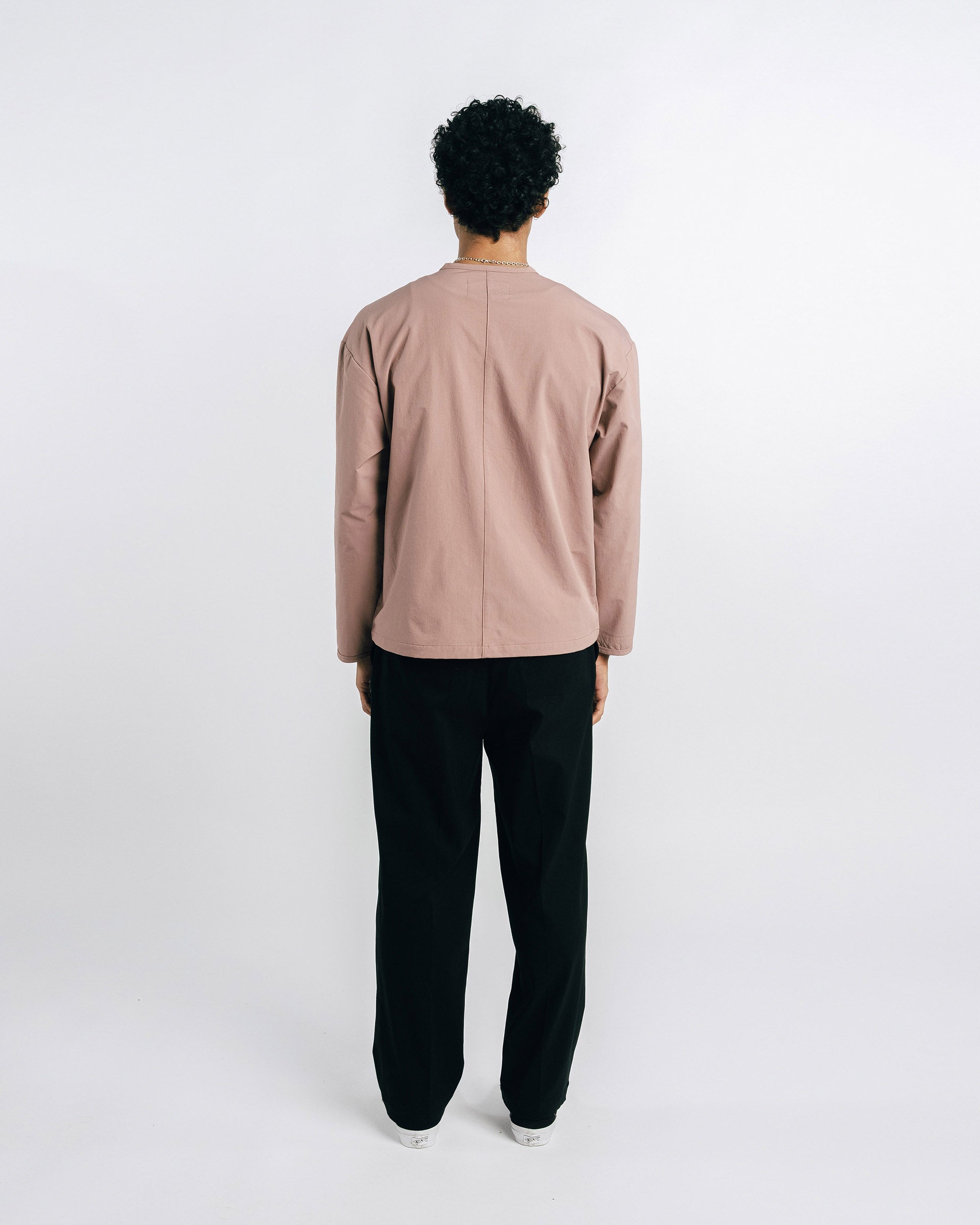 Person wearing a beige jacket and black pants on a white background