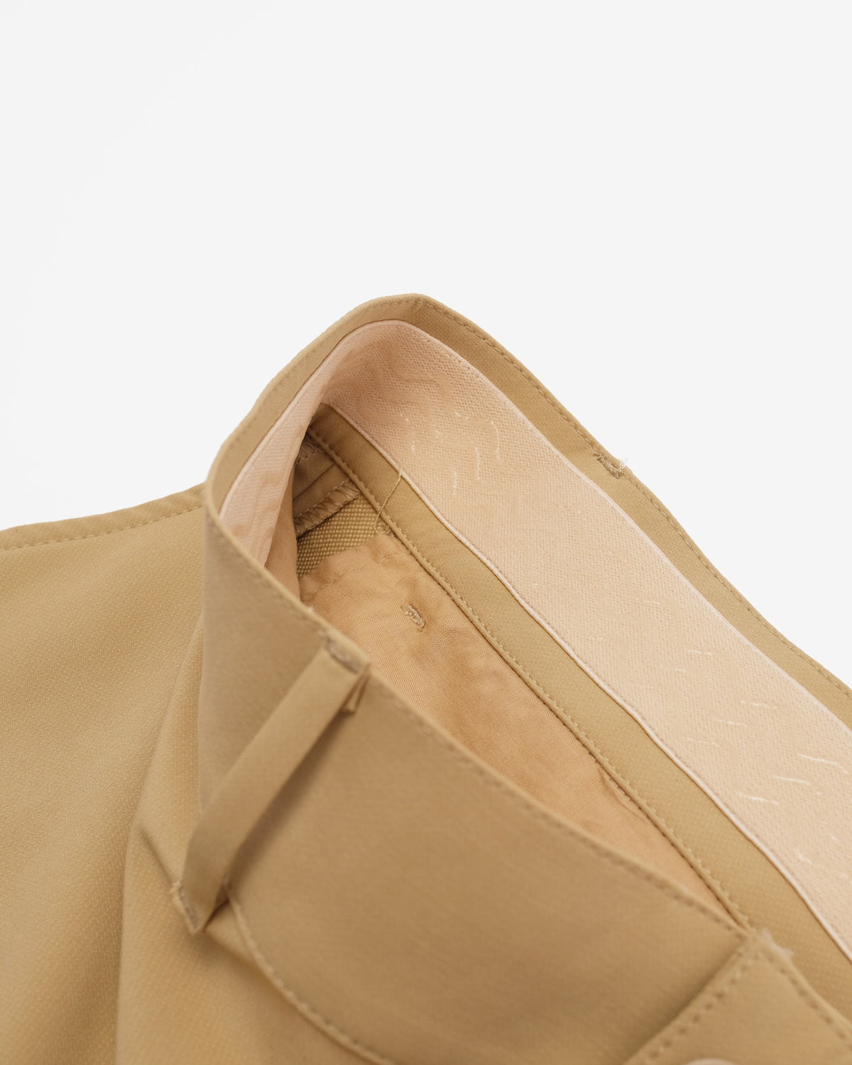 Close-up detail of a beige shoulder strap and inner lining of a bag against a plain white background.