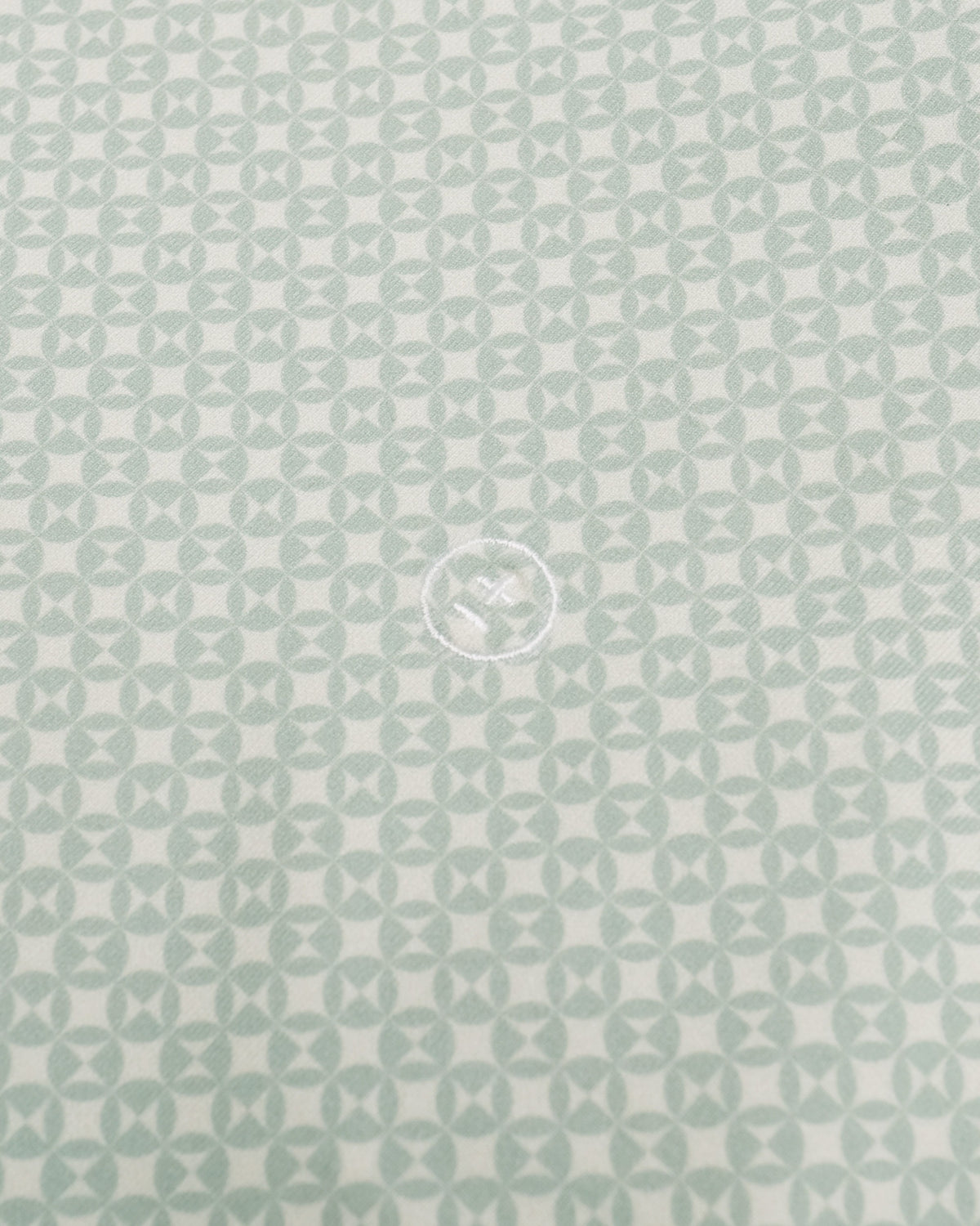 A close-up of a fabric or material swatch with a repeating geometric pattern in pale mint green on a white background.