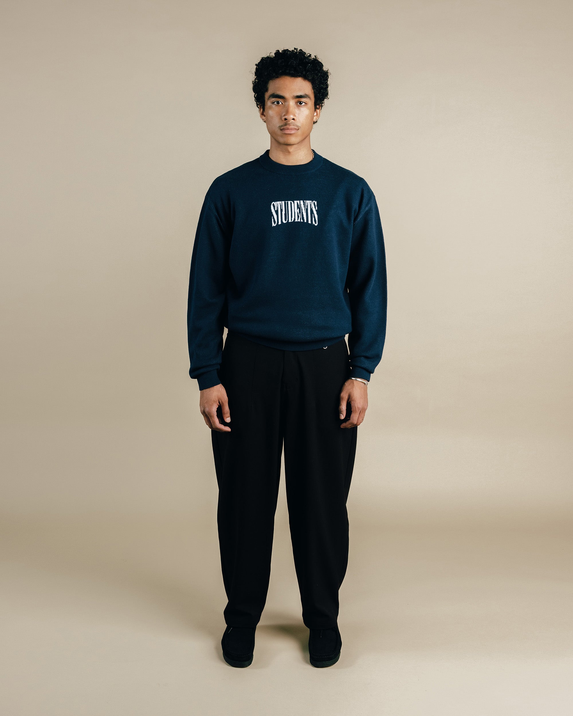 Person wearing a navy sweatshirt with 'STUDENTS' text on a beige background