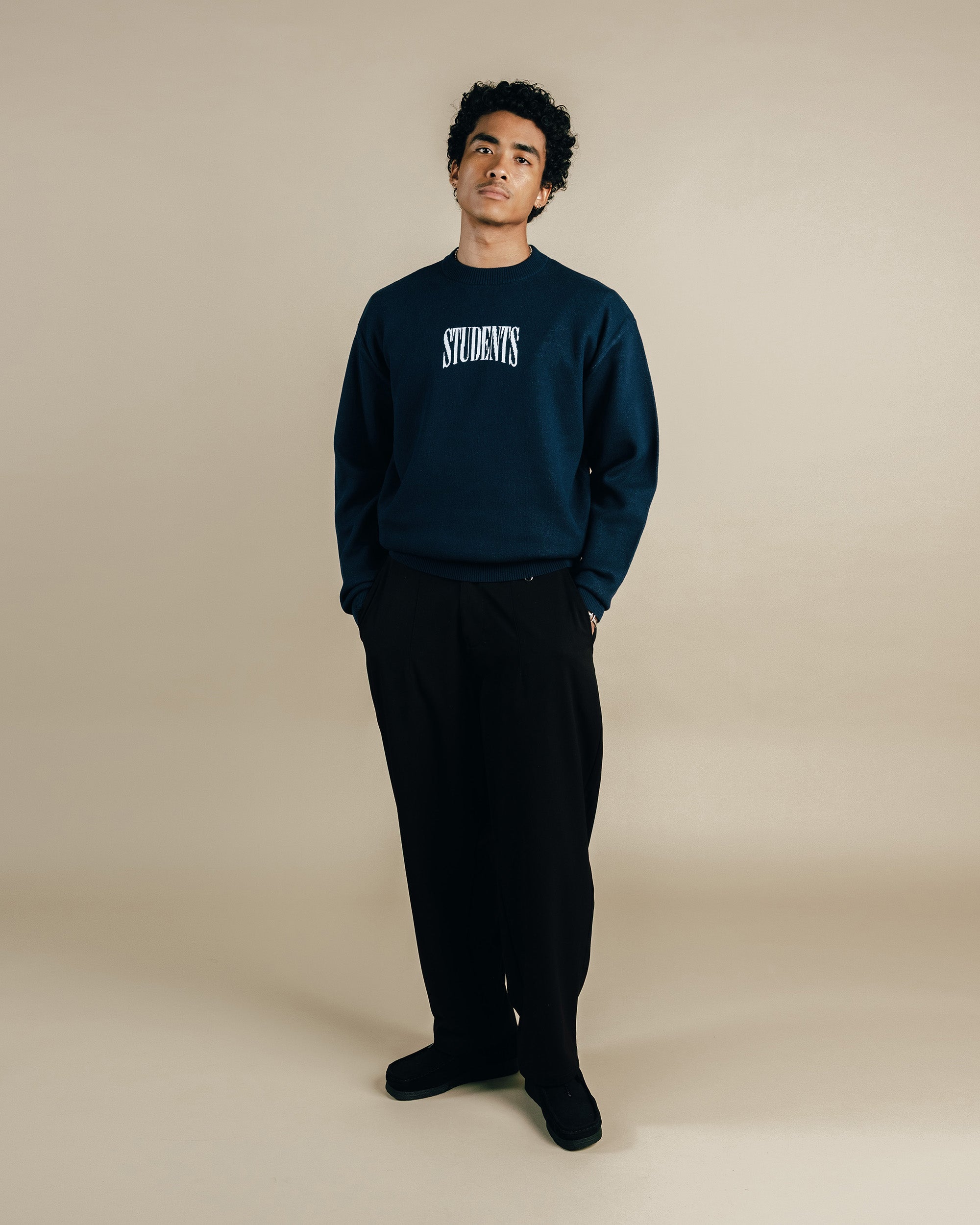 Person wearing a navy blue sweatshirt with 'STUDENTS' text on a beige background