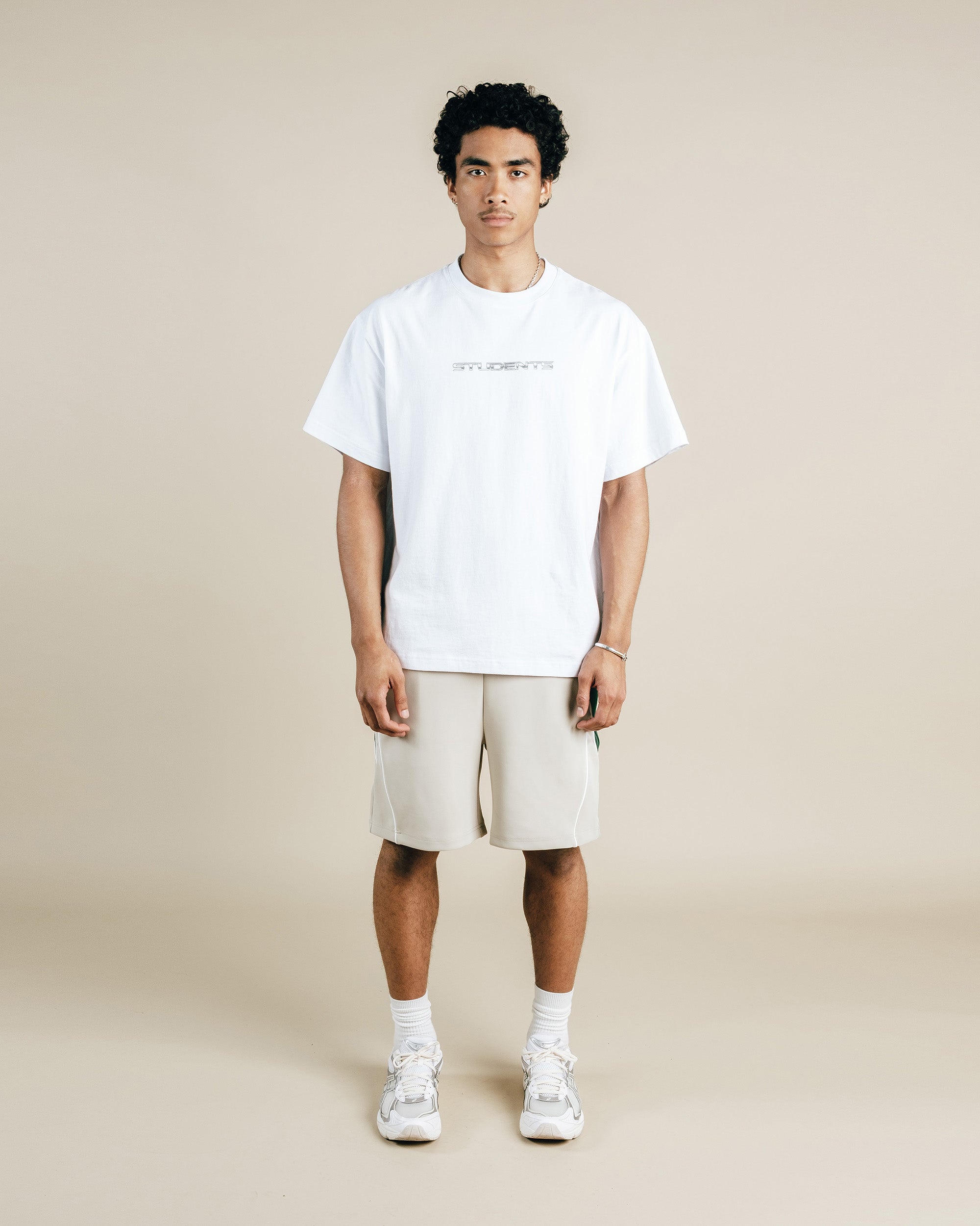 Person wearing a white t-shirt and beige shorts on a beige background