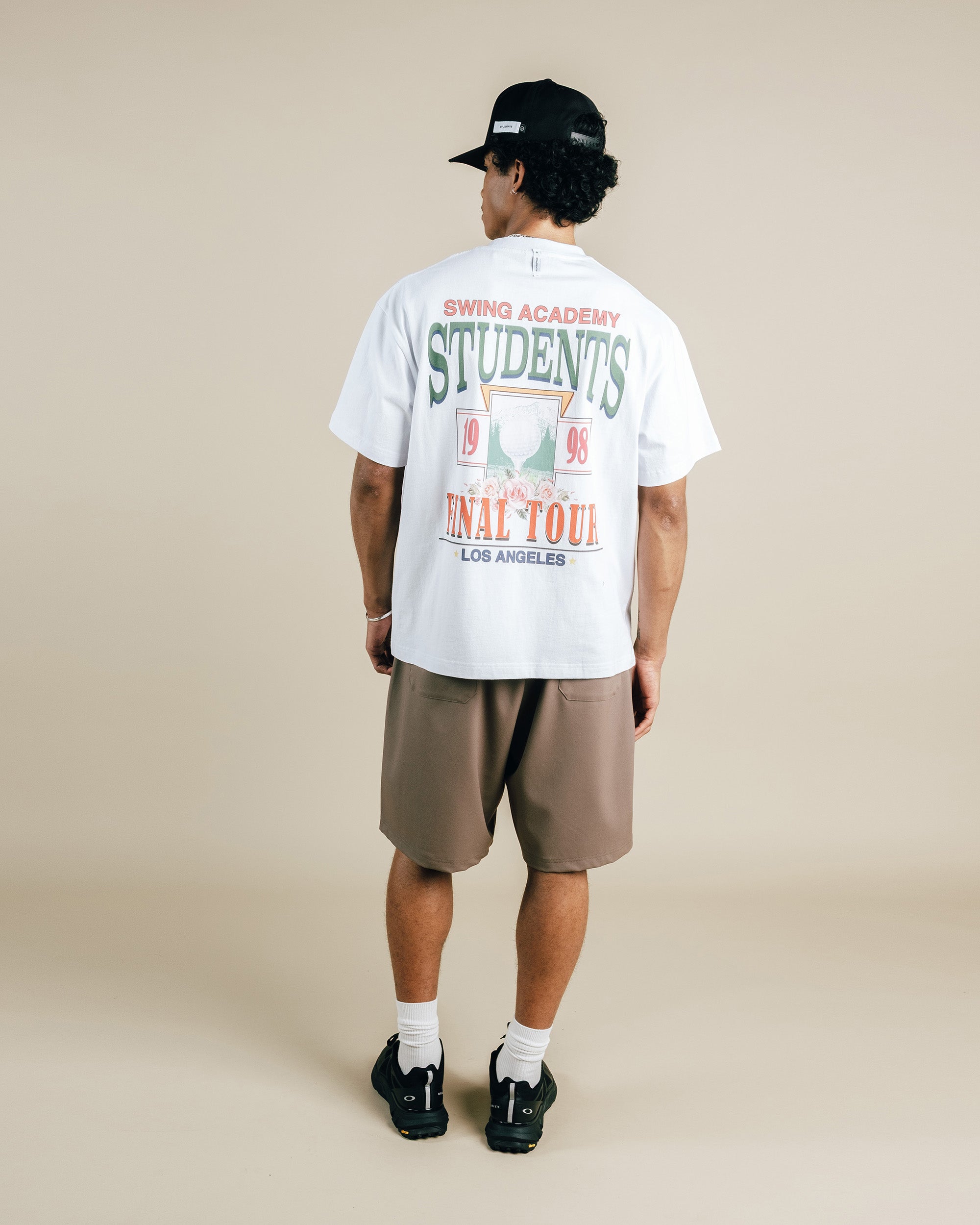 Person wearing a white t-shirt with text and graphics, standing against a beige background