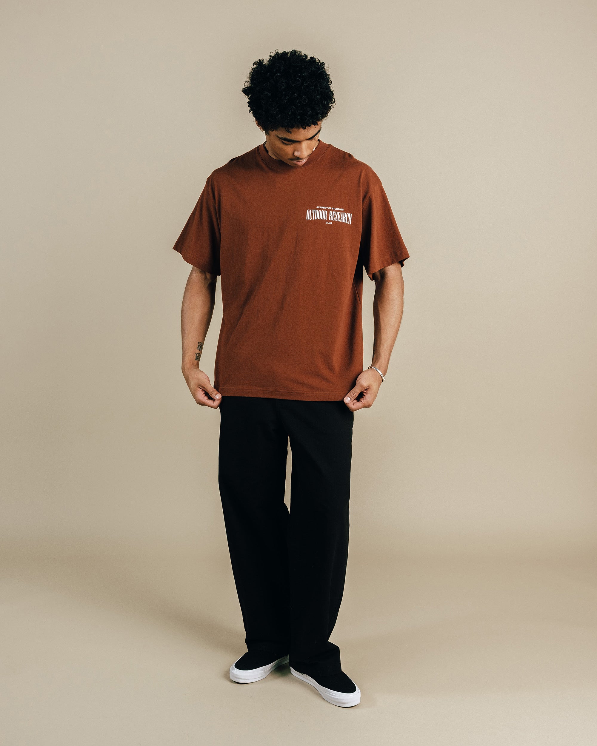 Person wearing a brown t-shirt with text on a beige background