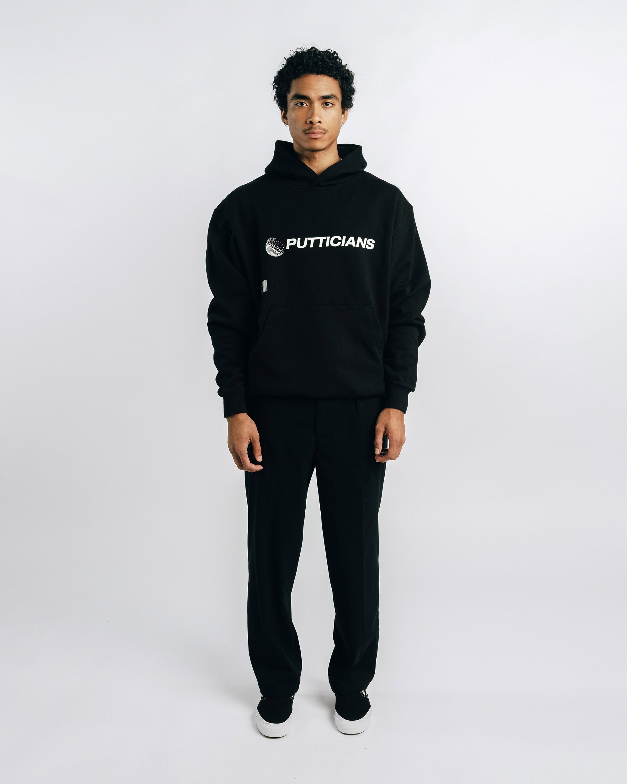 Person wearing a black hoodie with 'PUTTICIANS' text on a white background
