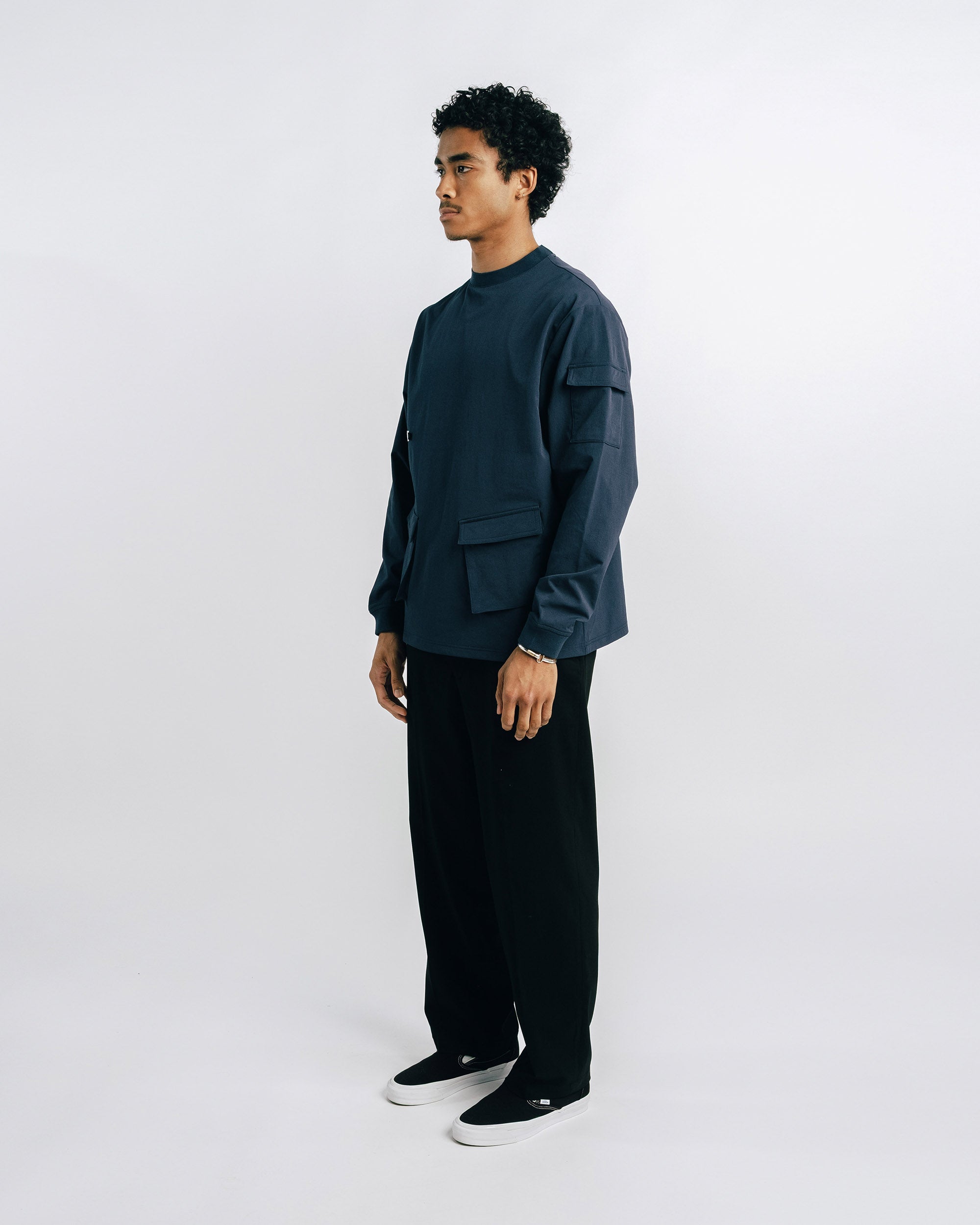 Person wearing a dark green shirt and black pants on a white background