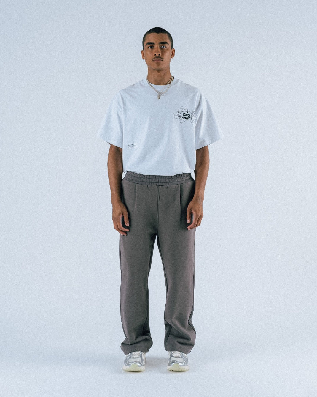 Person wearing a white t-shirt and gray pants on a white background