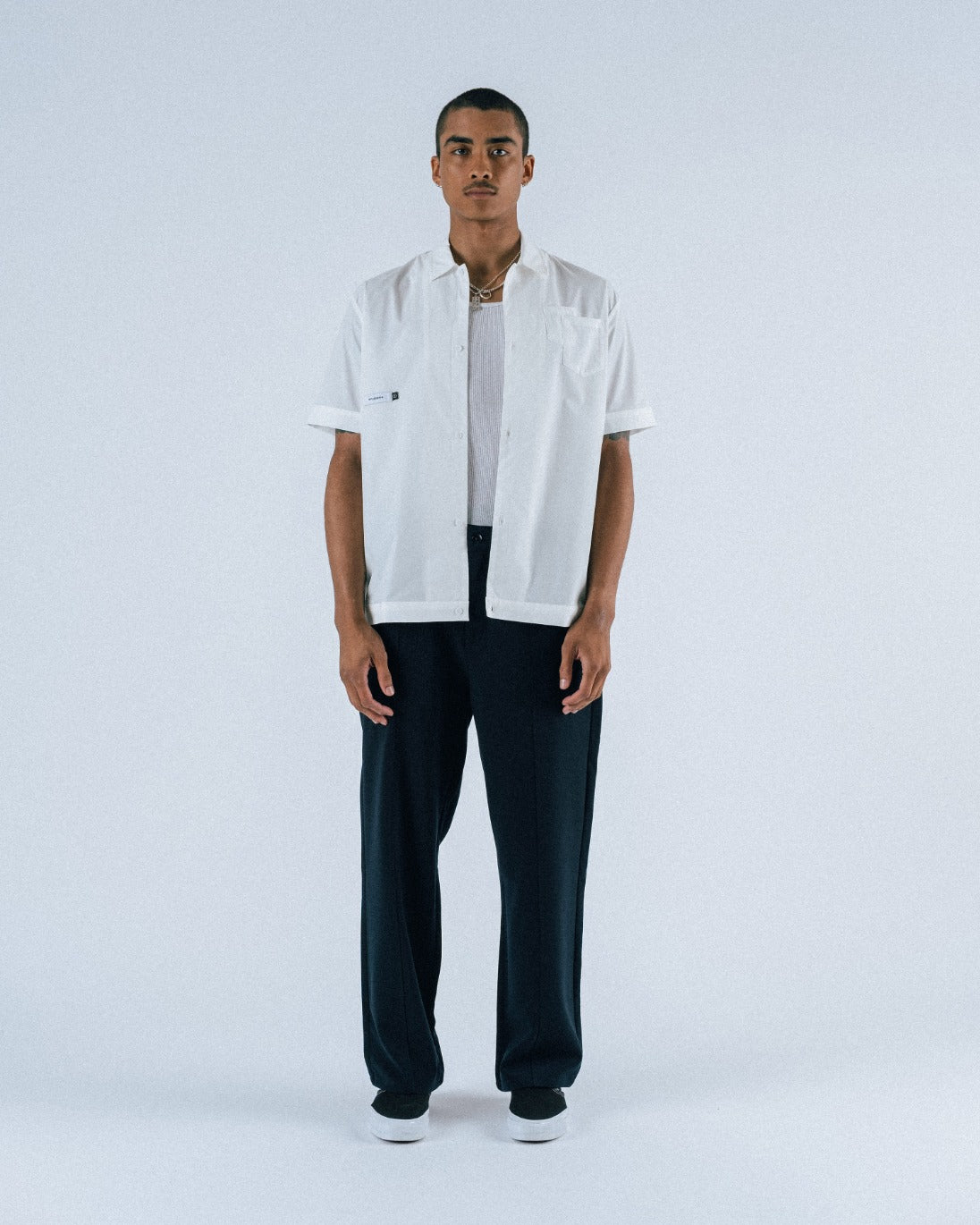 Person wearing a white shirt and dark pants on a white background