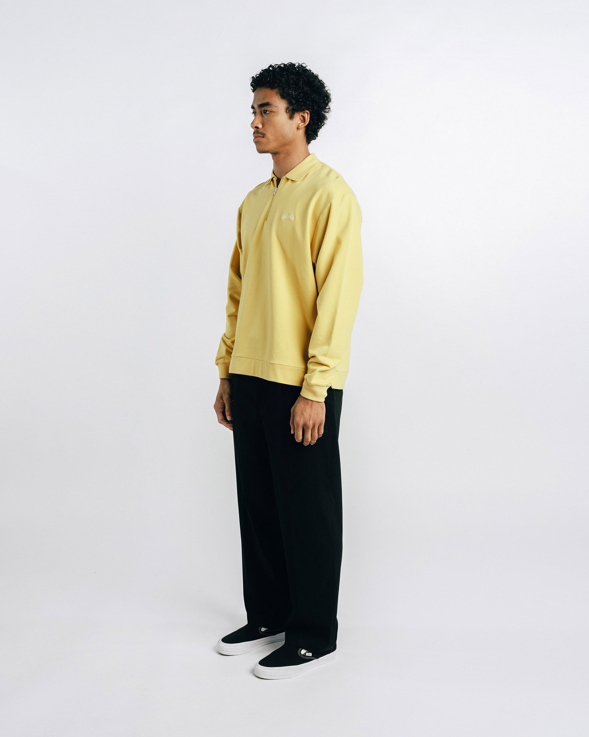Person wearing a yellow shirt and black pants on a white background