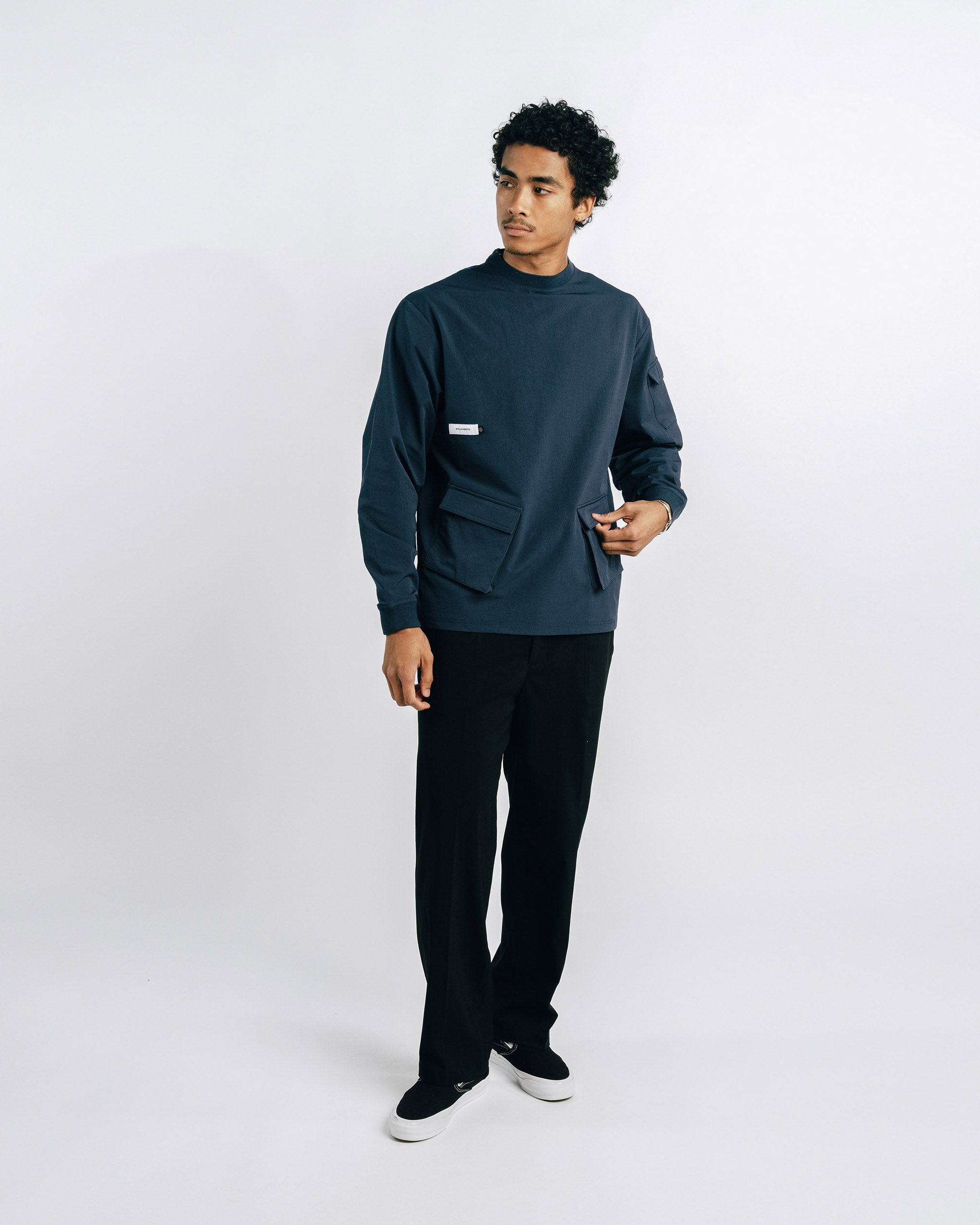 Person wearing a dark green sweater and black pants on a white background