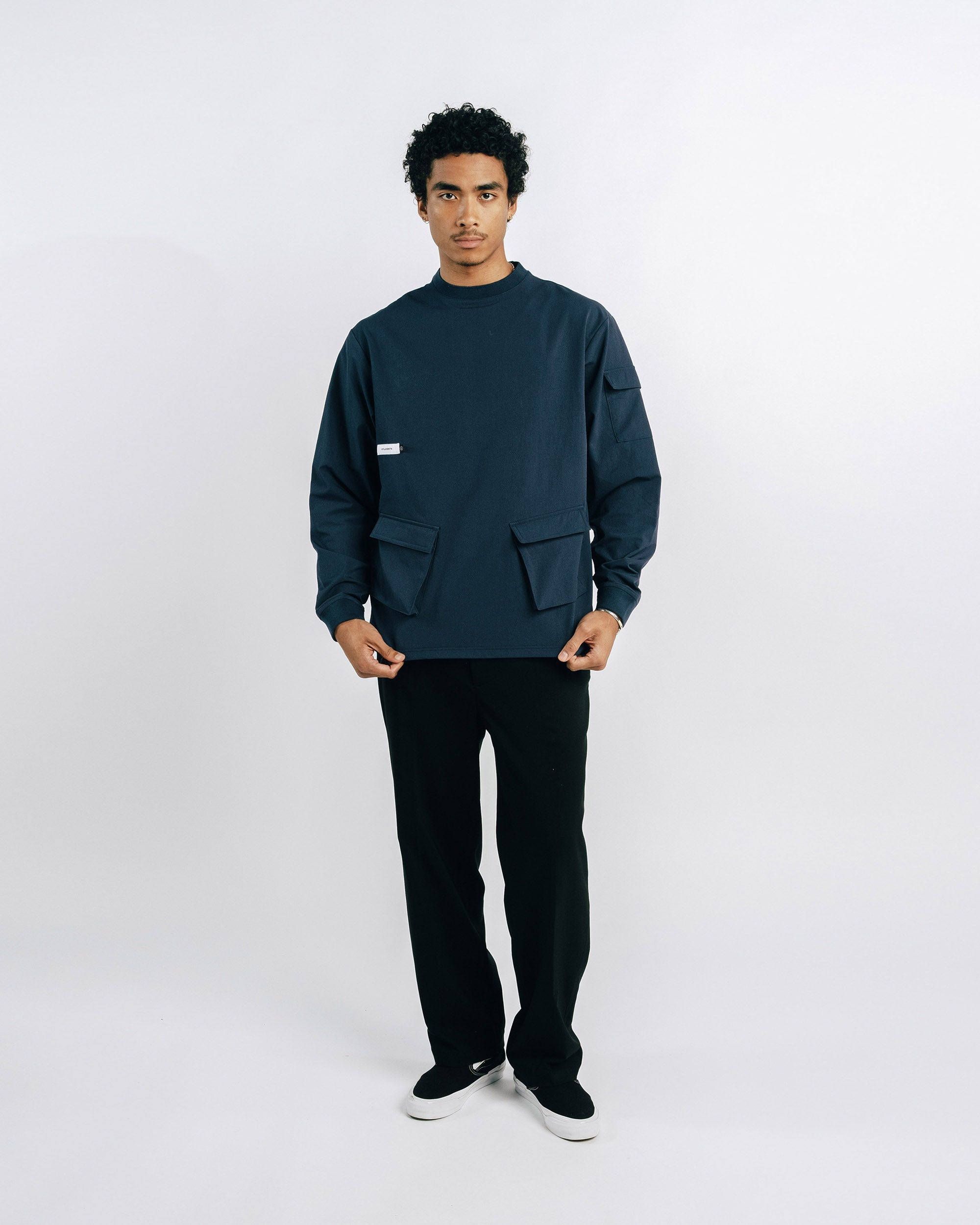 Person wearing a dark green sweater and black pants on a white background