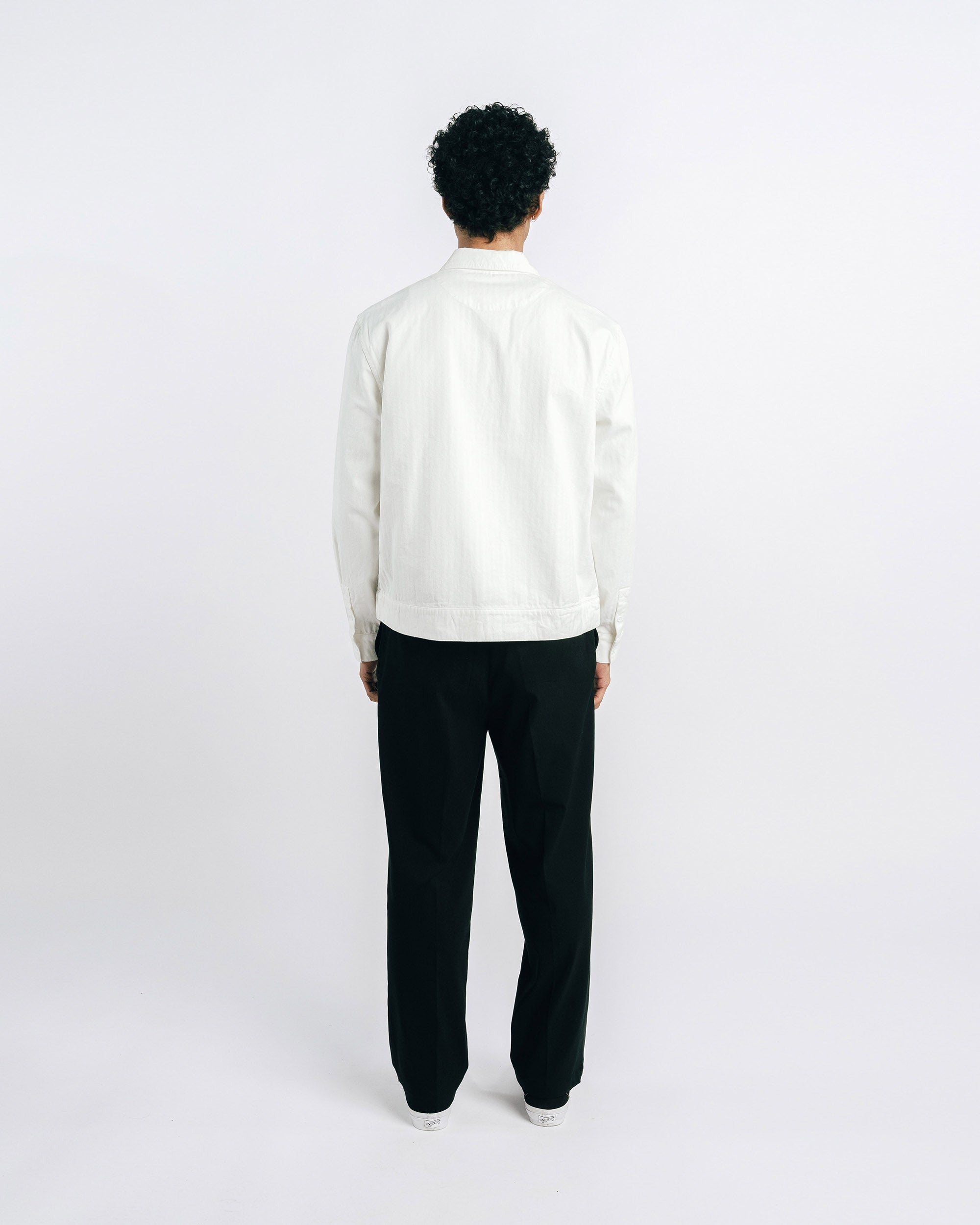 Man wearing a white shirt and black pants on a white background