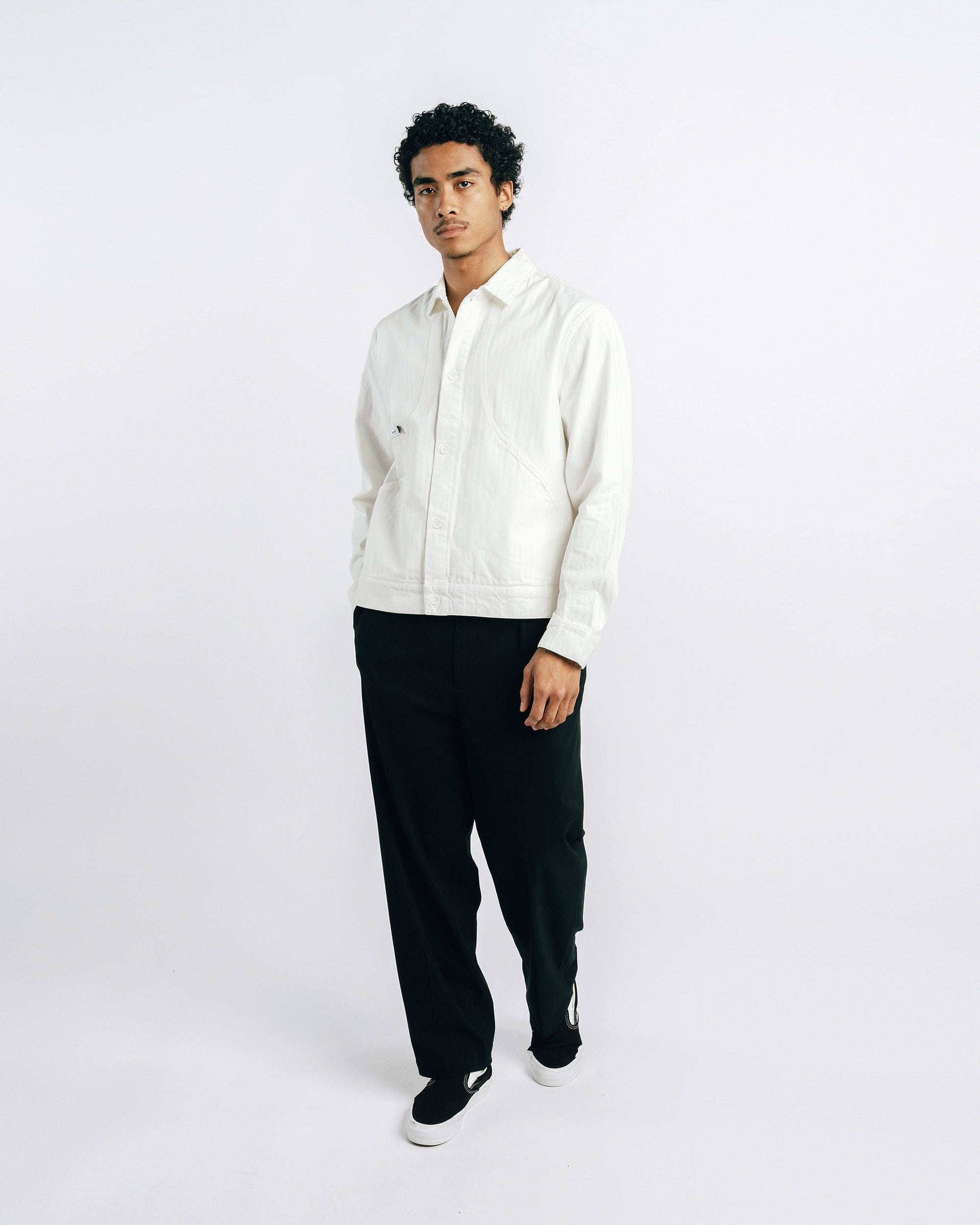 Person wearing a white shirt and black pants on a white background