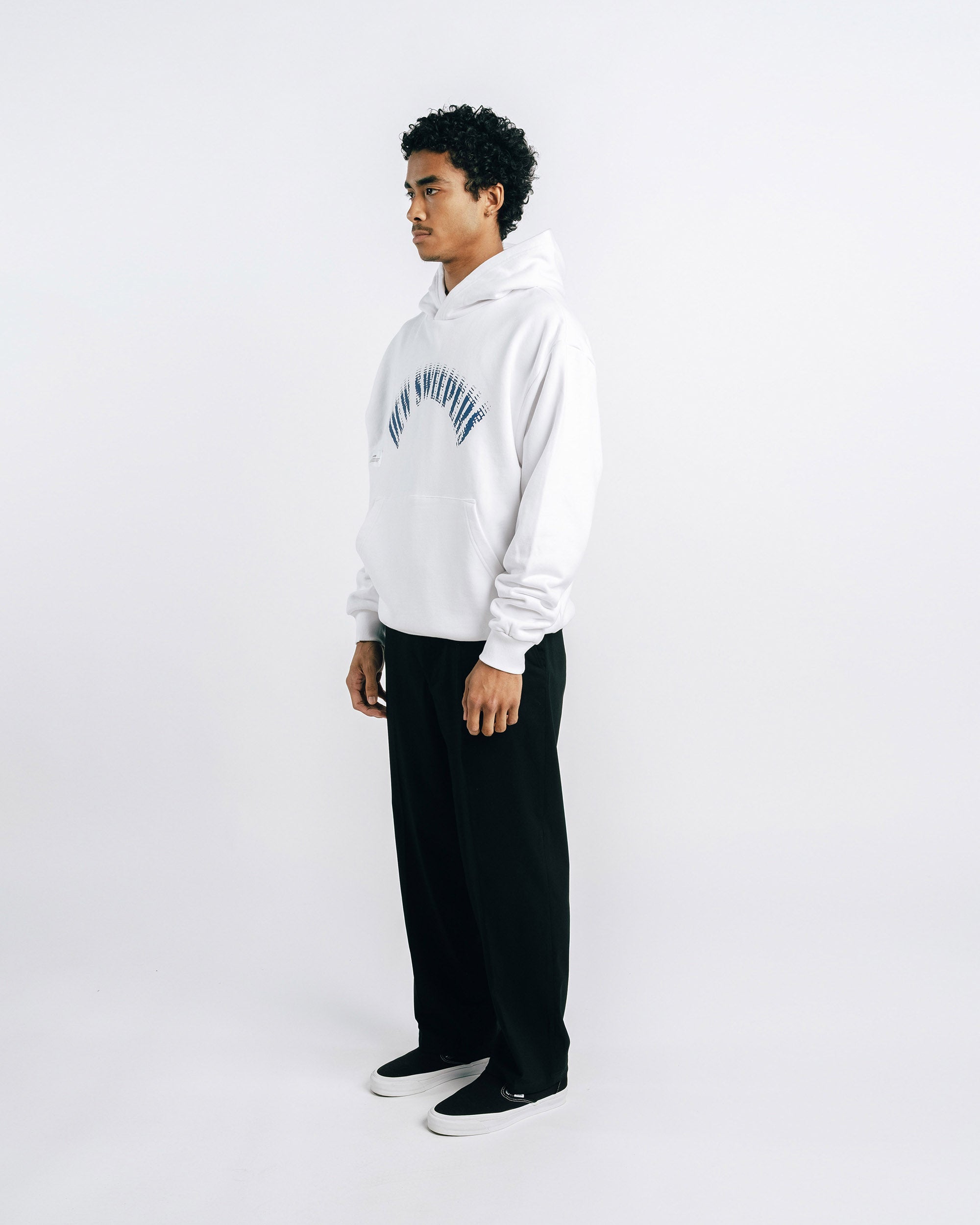 Person wearing a white hoodie with text and black pants on a white background