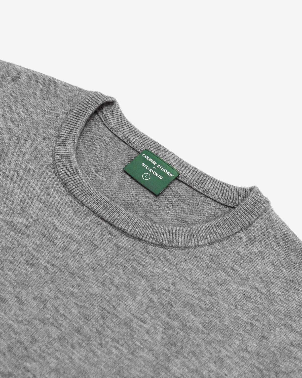 Close-up of a heather gray crewneck sweater showing the green neck label with white text that reads 'COLUMBUS STUDIOS'.