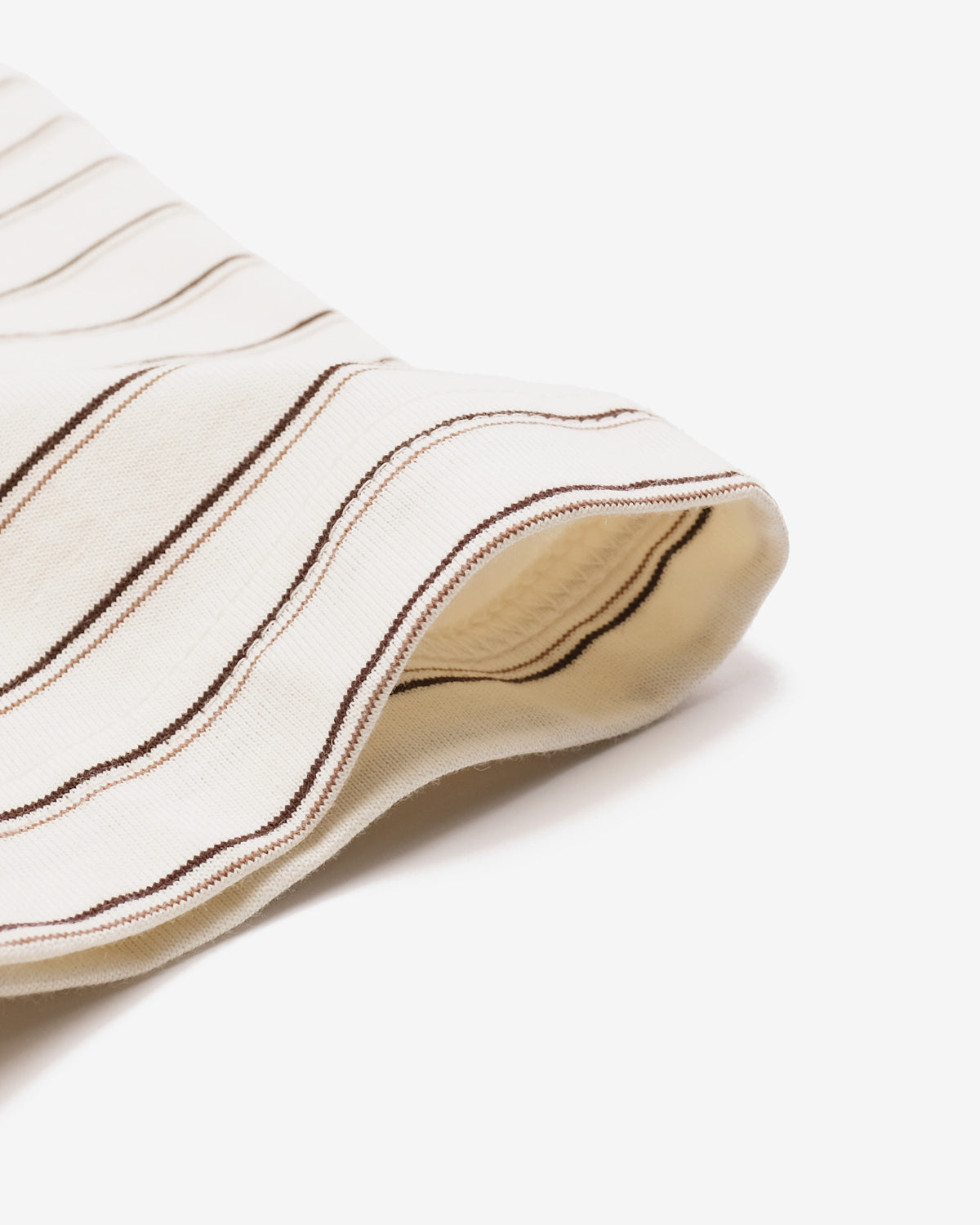 A close-up of a cream-colored knit fabric, likely a sock or scarf, featuring thin brown and beige stripes, folded over to show its soft texture and beige lining on a clean white background.
