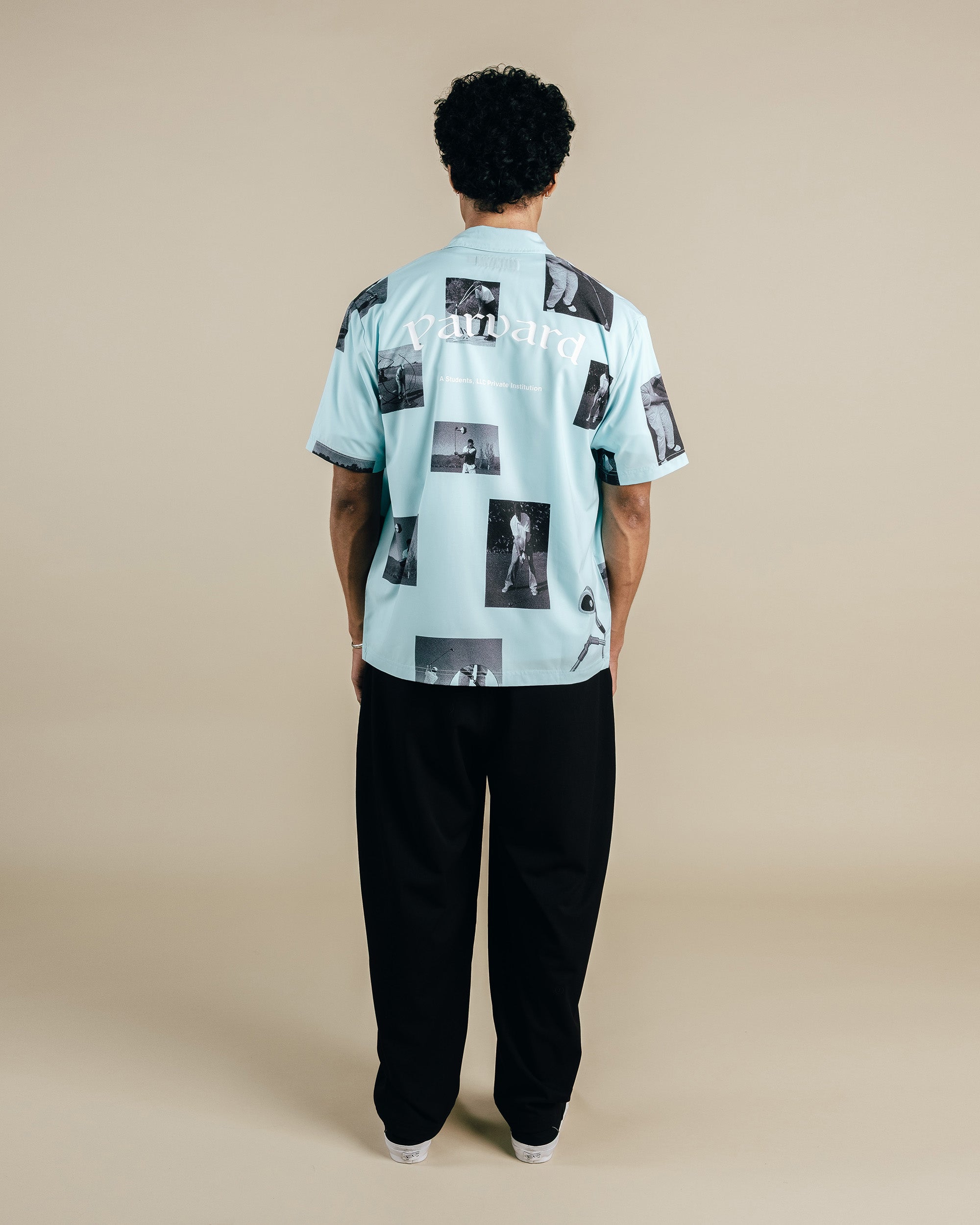 Person wearing a light blue shirt with black and white photo print on a beige background