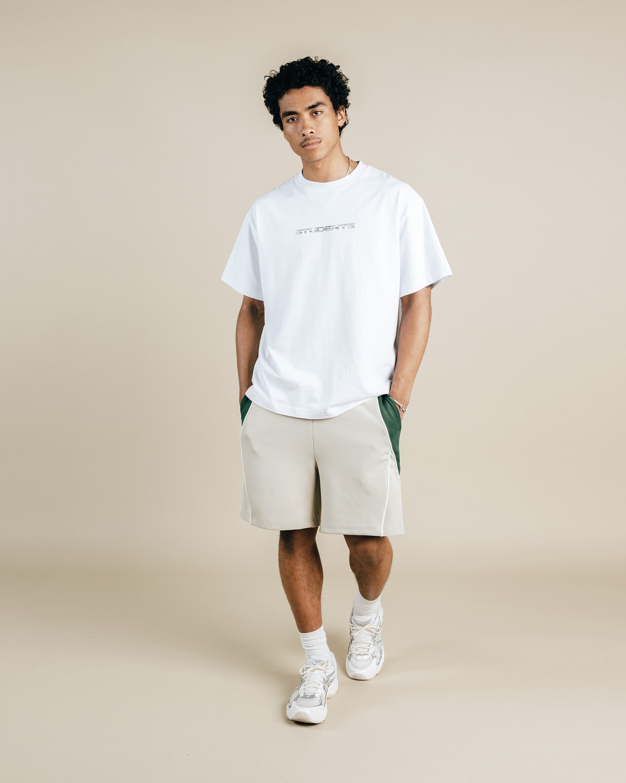 Person wearing a white t-shirt and beige shorts on a plain background