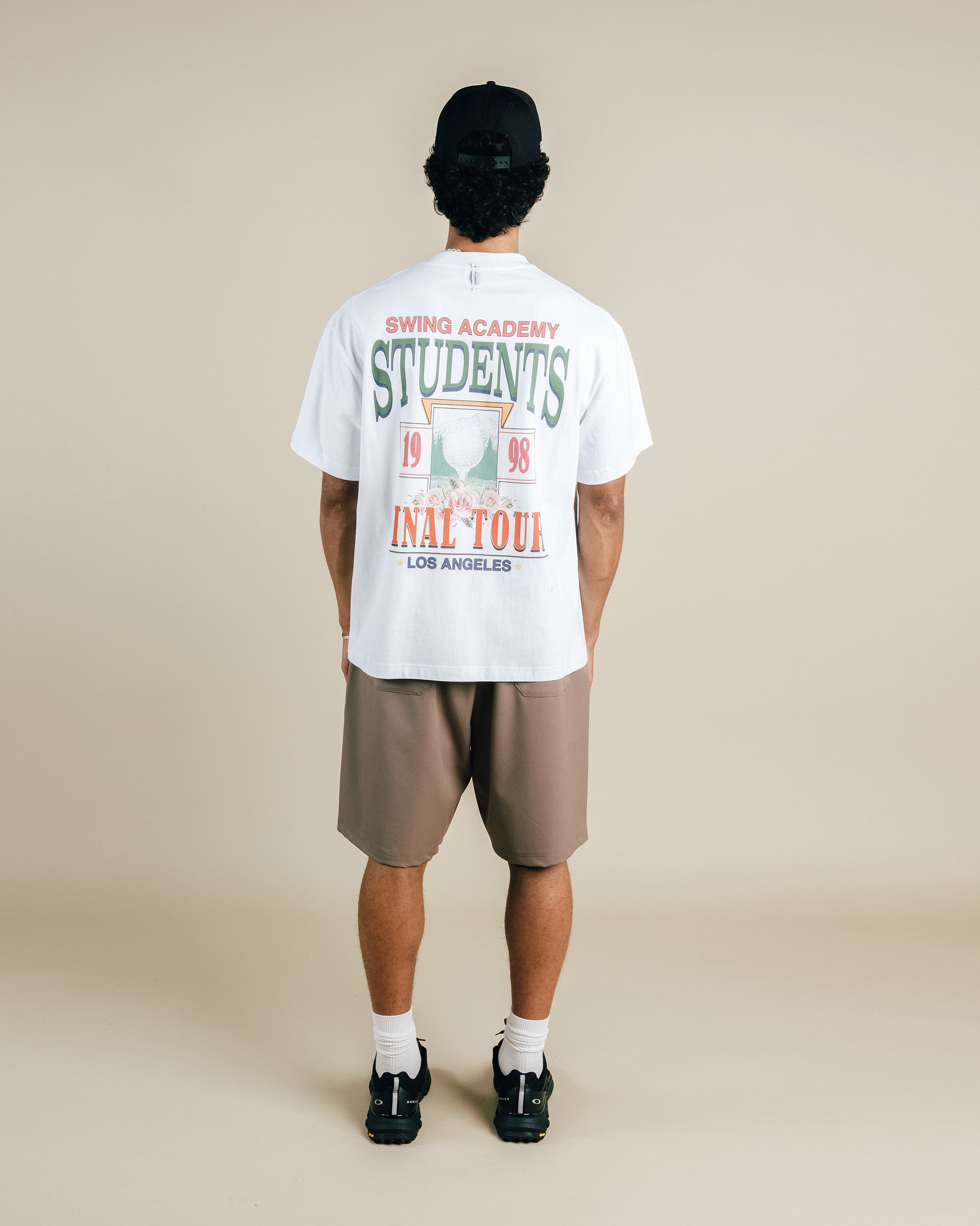 Person wearing a white t-shirt with text and graphics, standing against a beige background